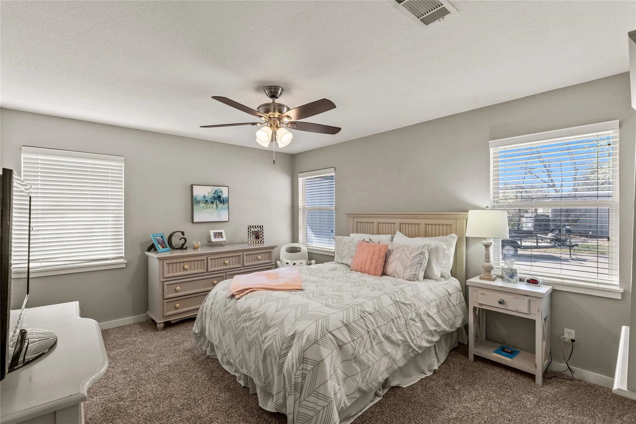 Carpeted bedroom featuring multiple windows and a ceiling fan