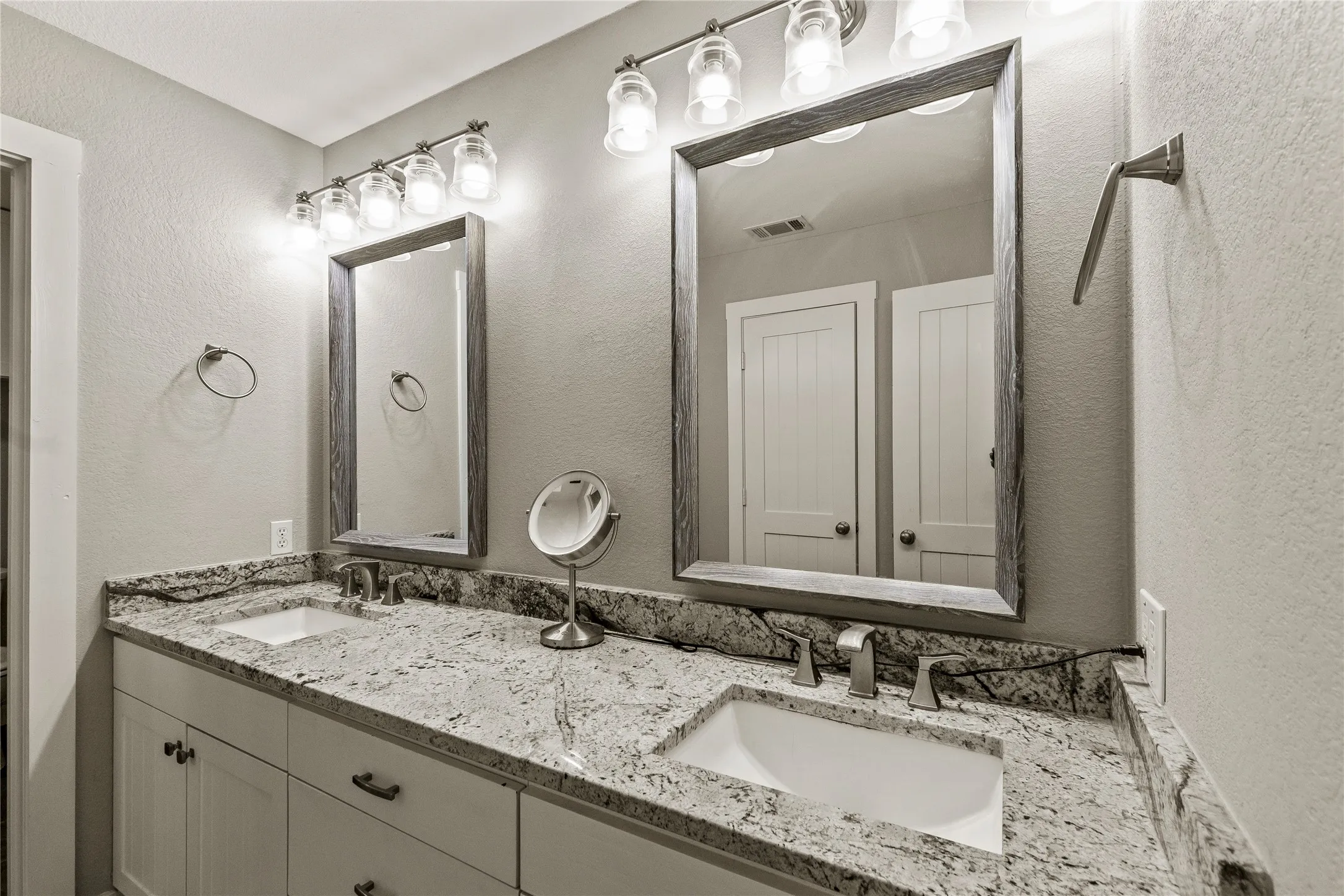 Full bathroom with a textured wall and double vanity