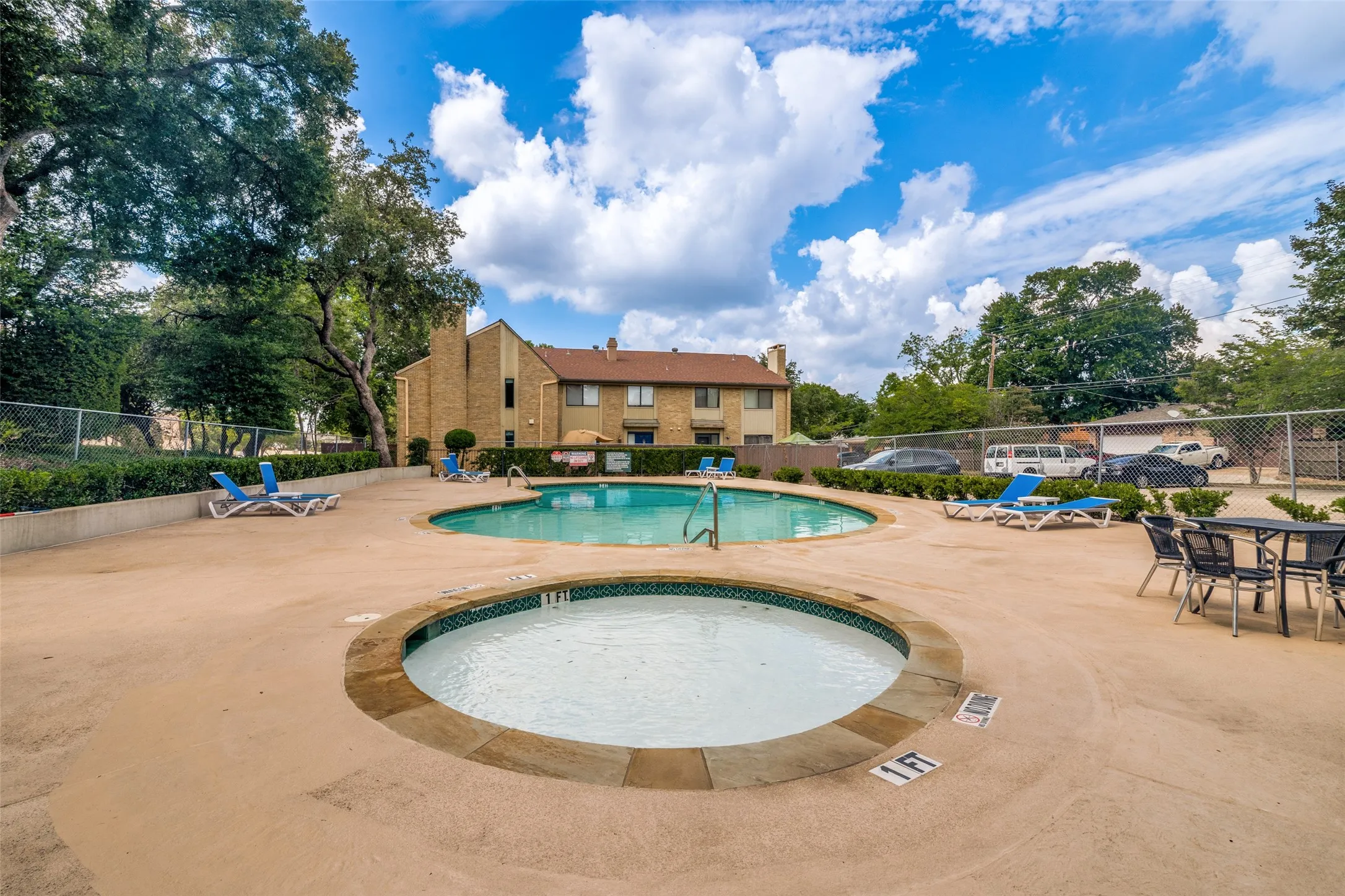 Resort-style pool area featuring a large swimming pool and an adjacent circular spa