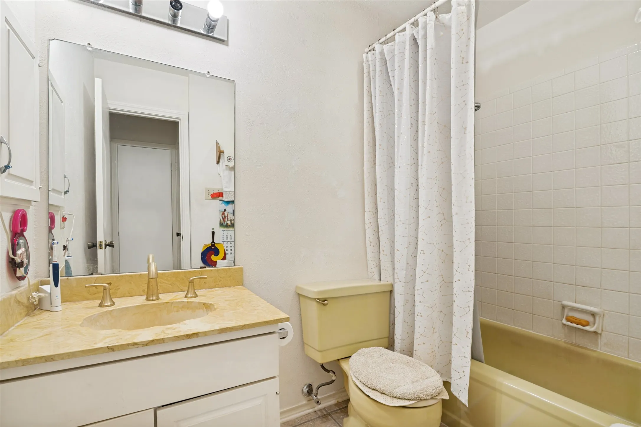 Bathroom featuring a vanity with a light-toned countertop, an undermount sink, and a three-bulb vanity light fixture