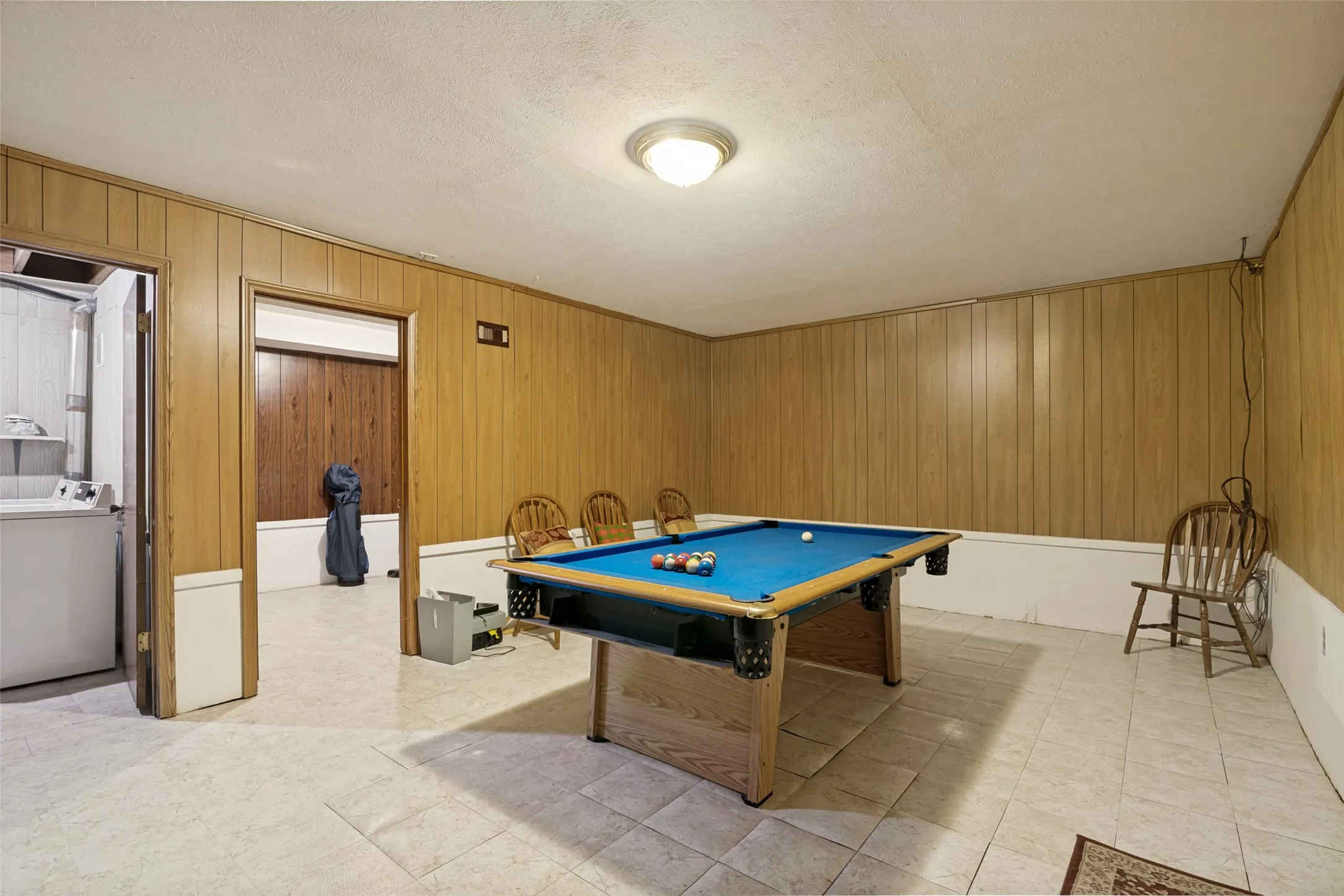 Recreation room featuring wood-finish wall paneling, tiled flooring, and a flush-mount ceiling light