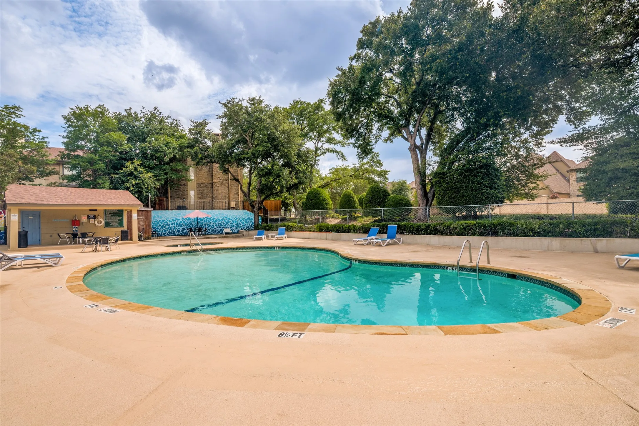 Freeform swimming pool with integrated spa and surrounding concrete decking