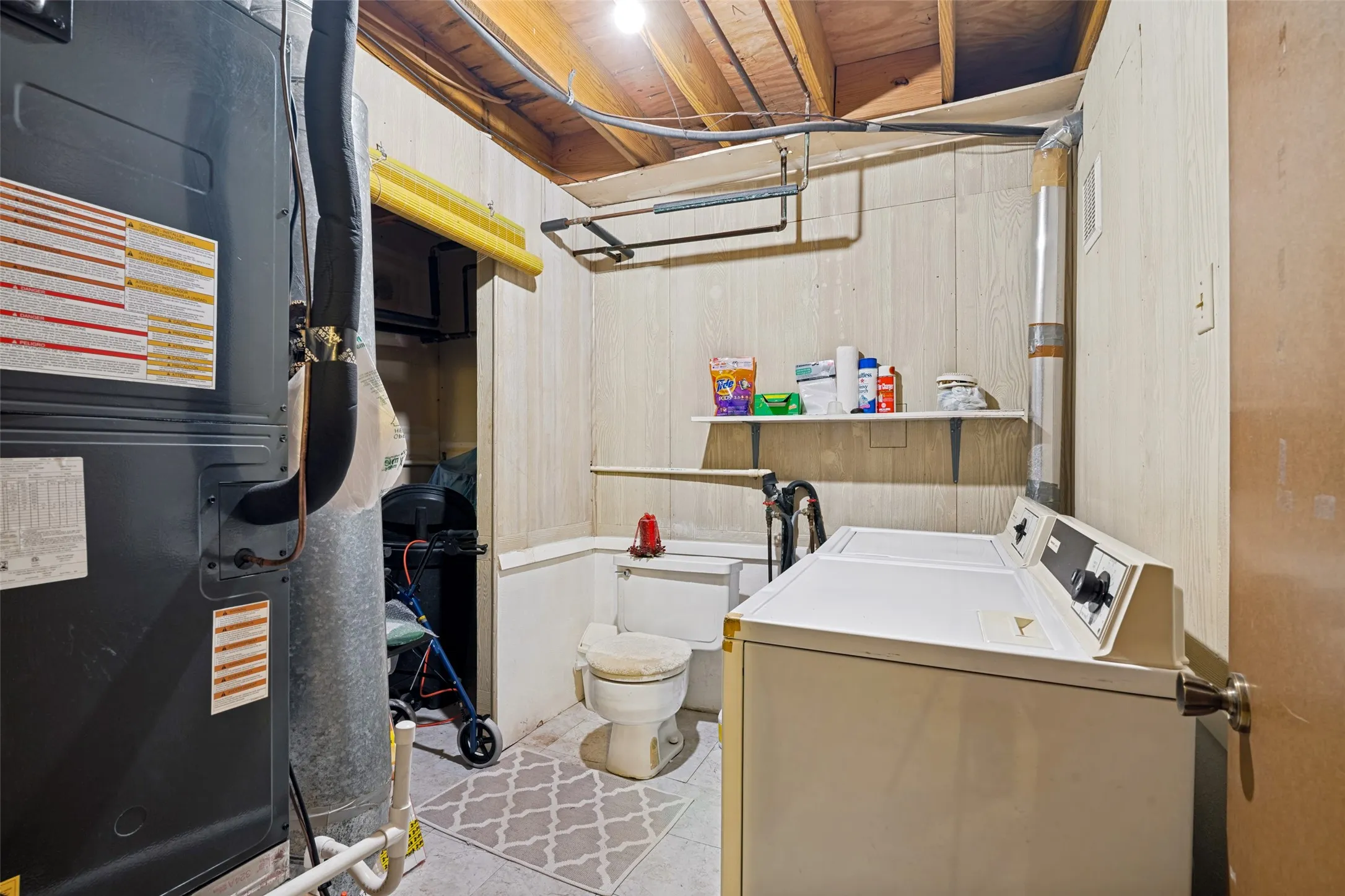 Utility room featuring a furnace, exposed ceiling joists, and paneling walls