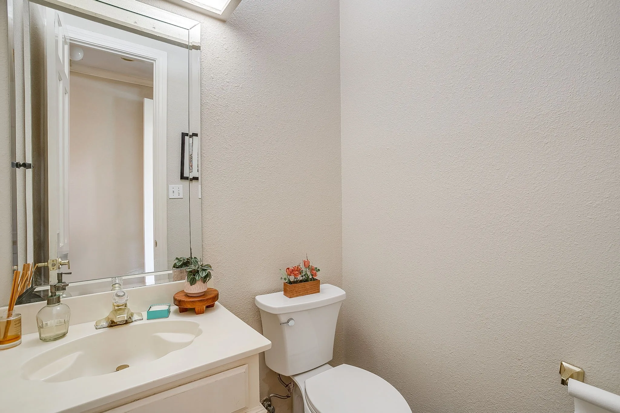 Powder room featuring a white vanity with integrated sink, a beveled mirror, and toilet
