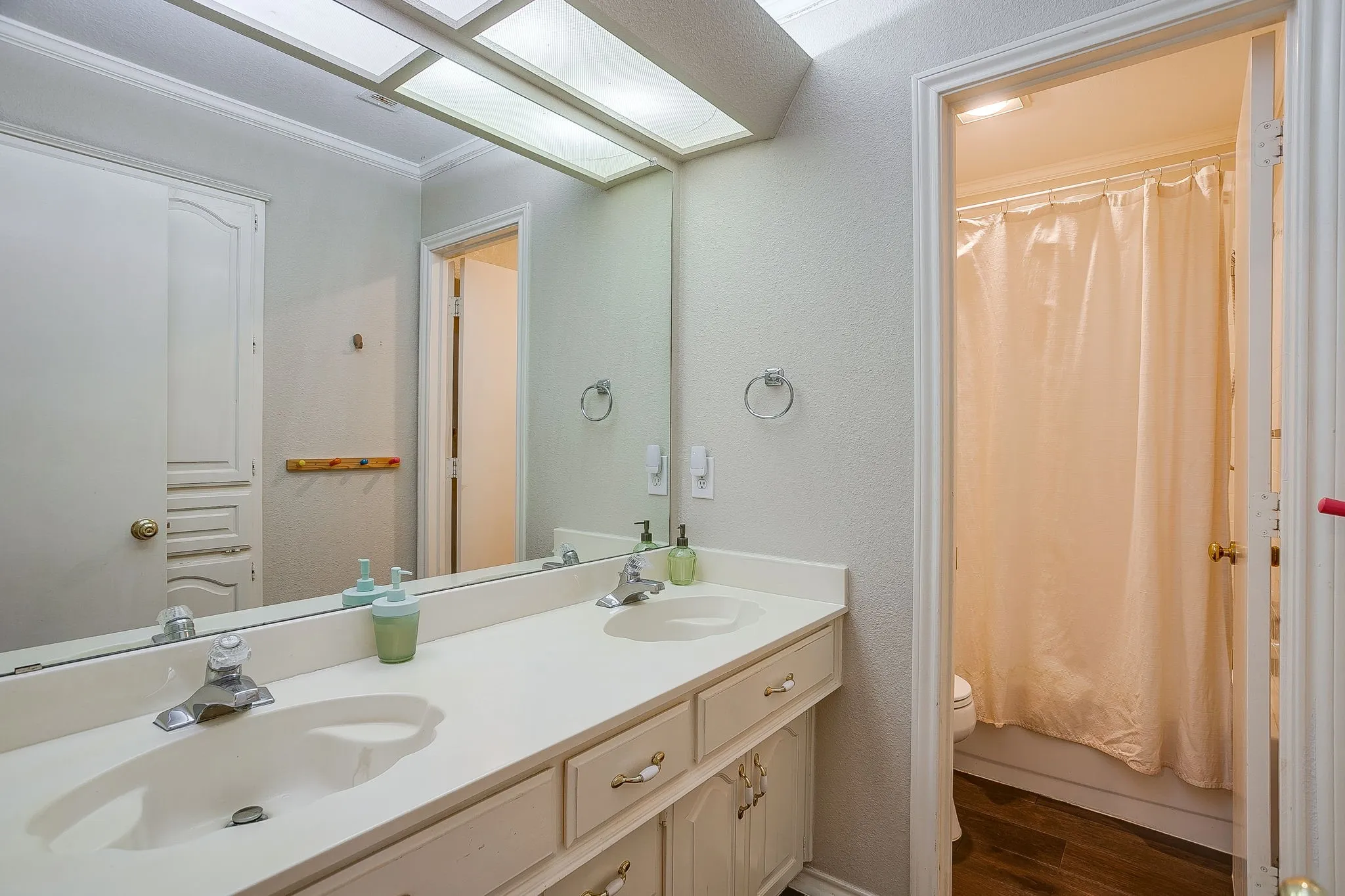 Dual sink vanity with white countertops and white cabinetry. Combo tub/shower attached