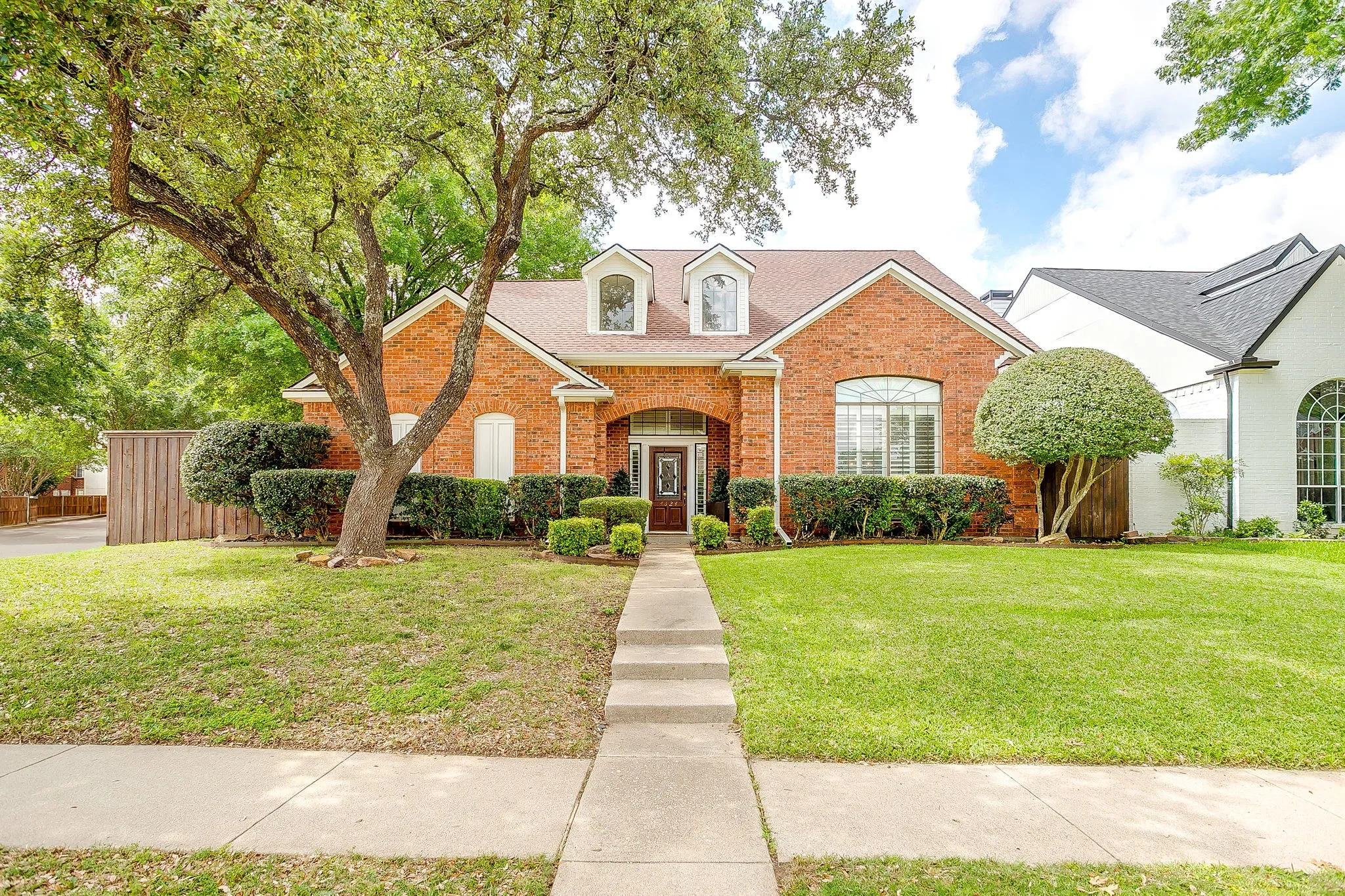 Traditional brick exterior with an arched entry, a prominent front-facing window with shutters, and a dormer window