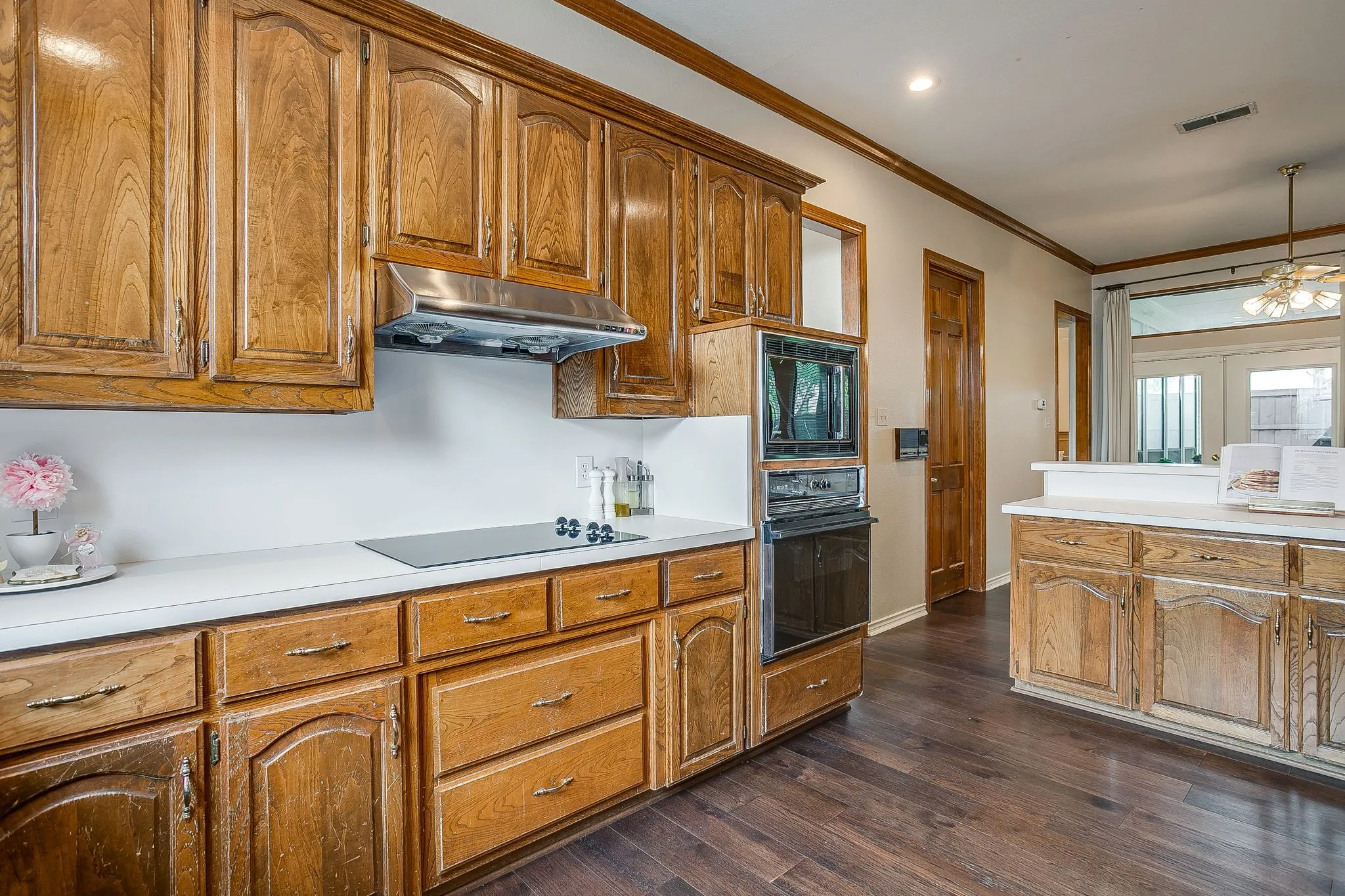 Kitchen featuring wood-finish cabinetry, white countertops, a built-in oven, a built-in microwave and cooktop