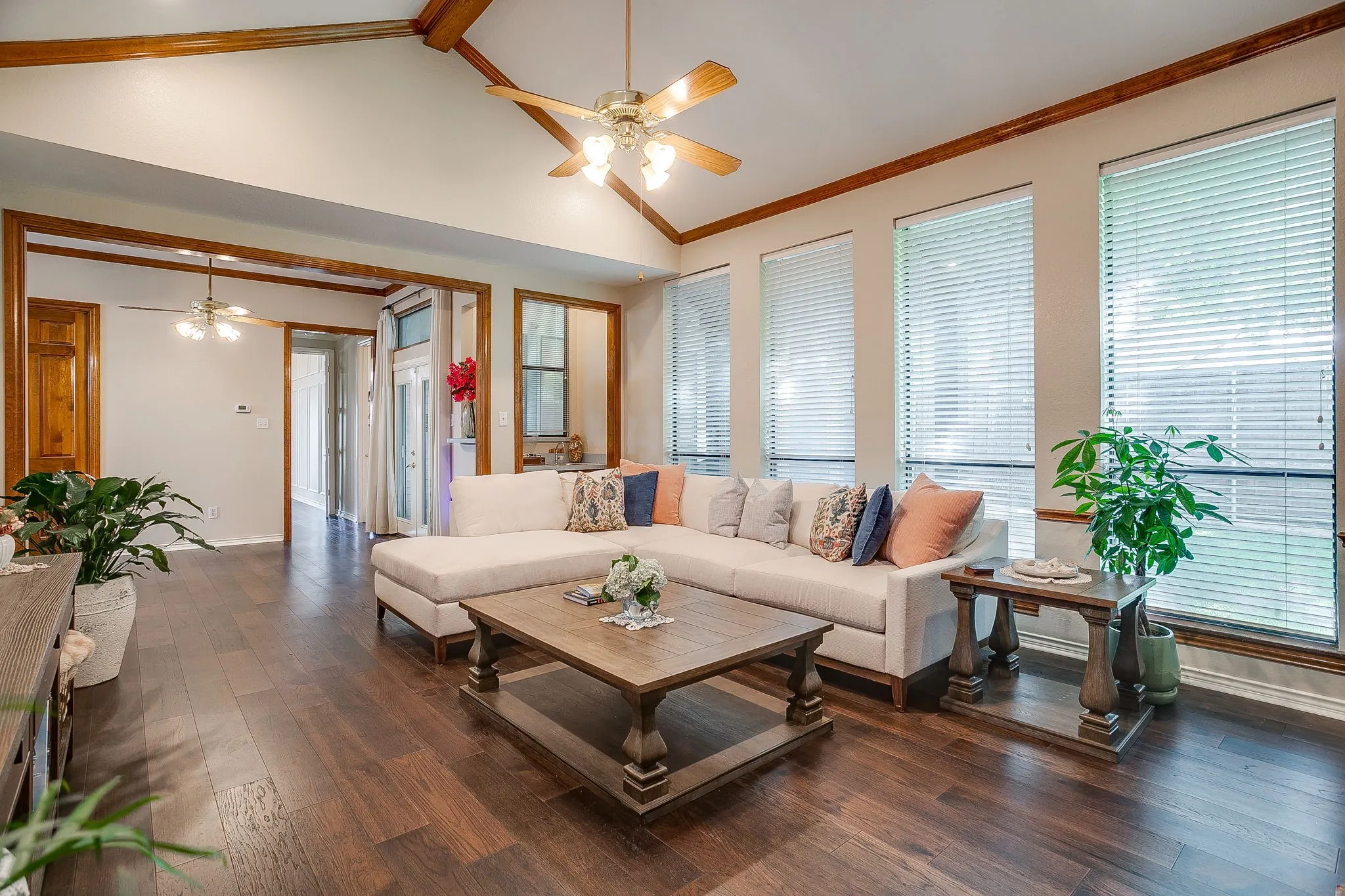 Living space featuring wood-finish flooring, vaulted ceilings with exposed wood beams, and multiple windows