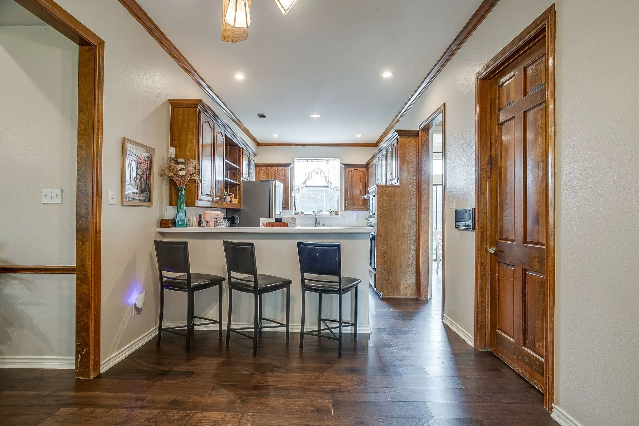 Galley kitchen featuring wood-finish cabinetry, a white countertop, and a breakfast bar