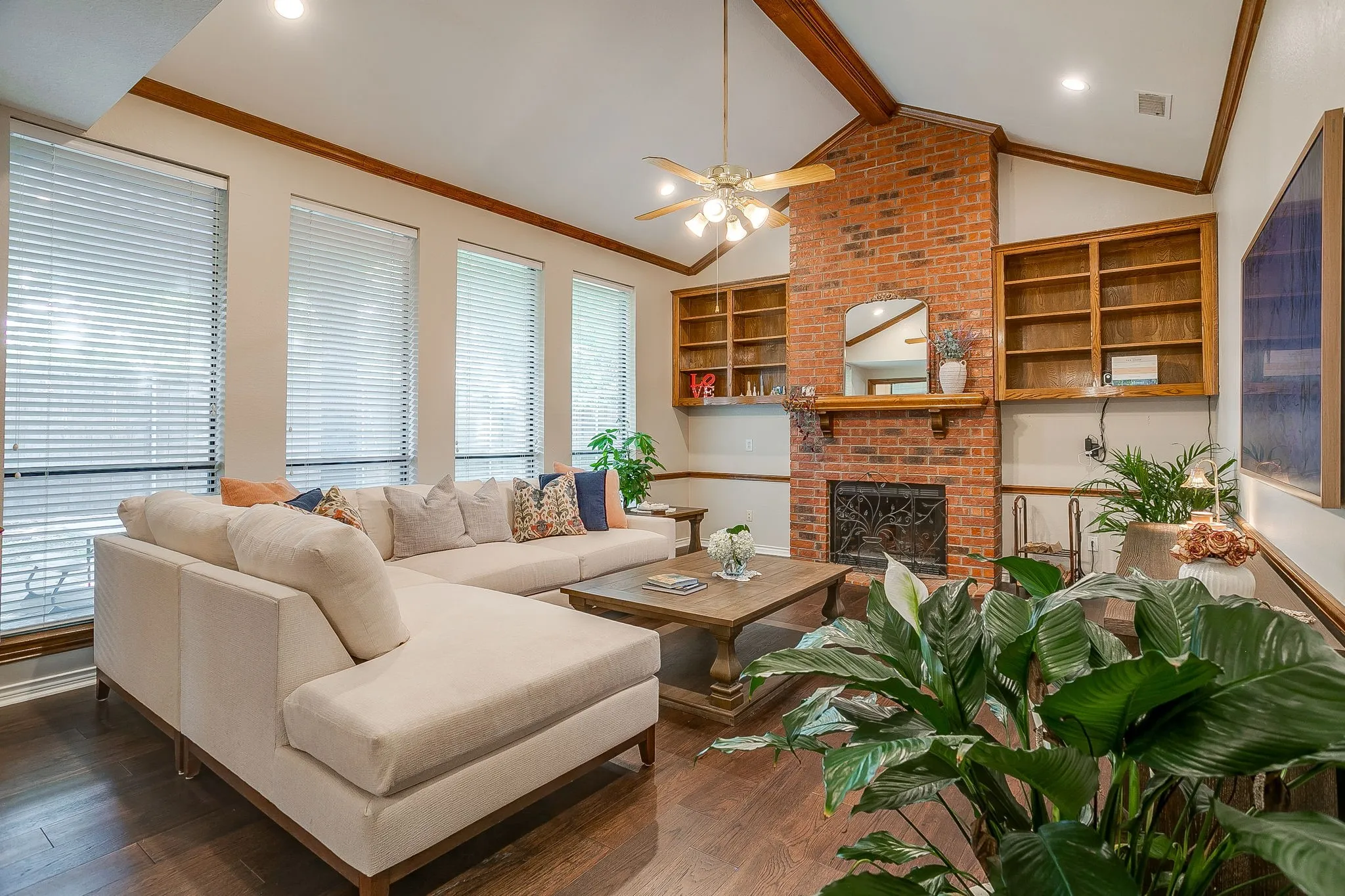 Living area featuring a brick fireplace with an ornate screen, wood mantle, and built-in shelving