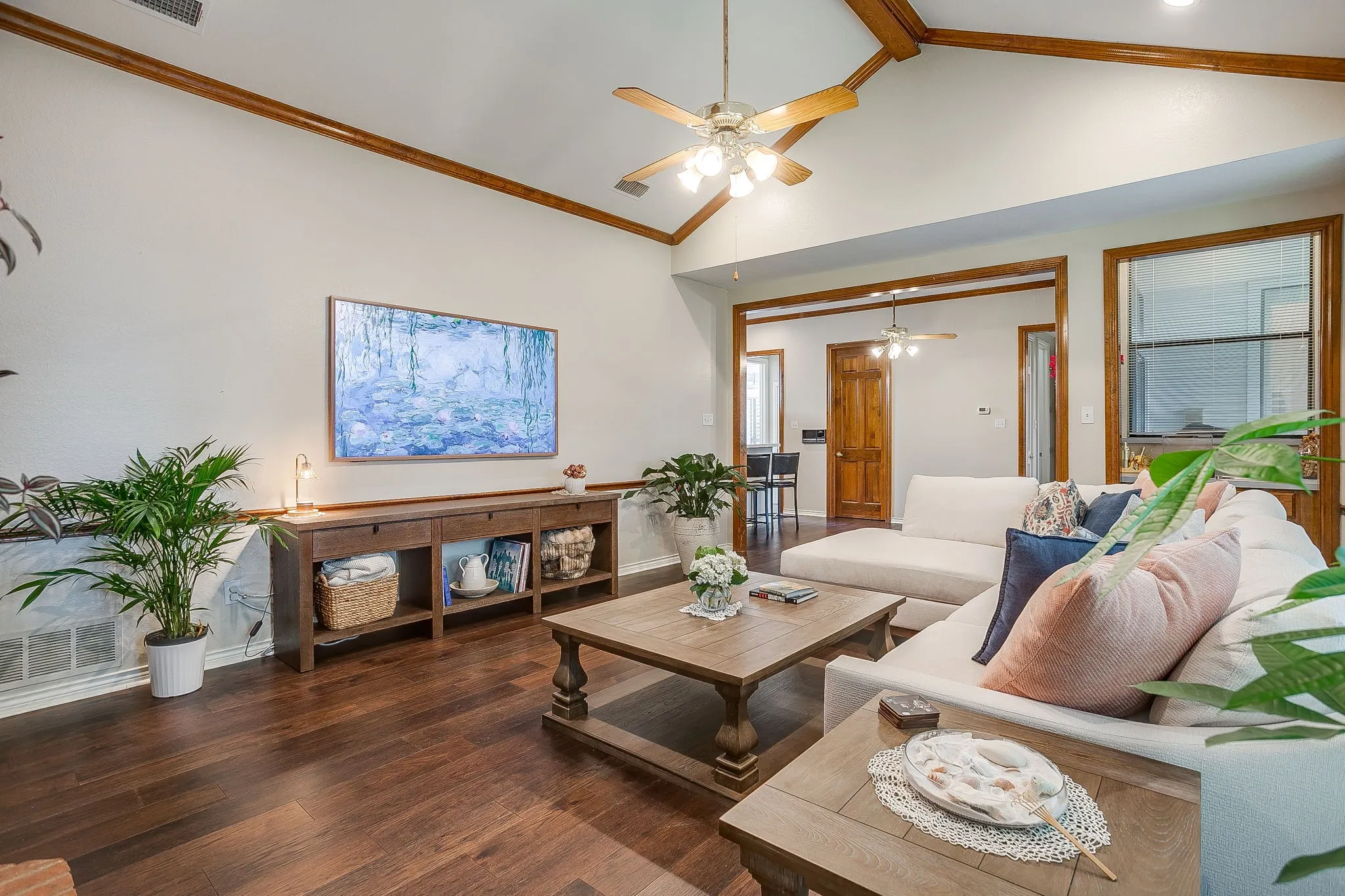 Living area featuring a vaulted ceiling with exposed wood beams and a ceiling fan