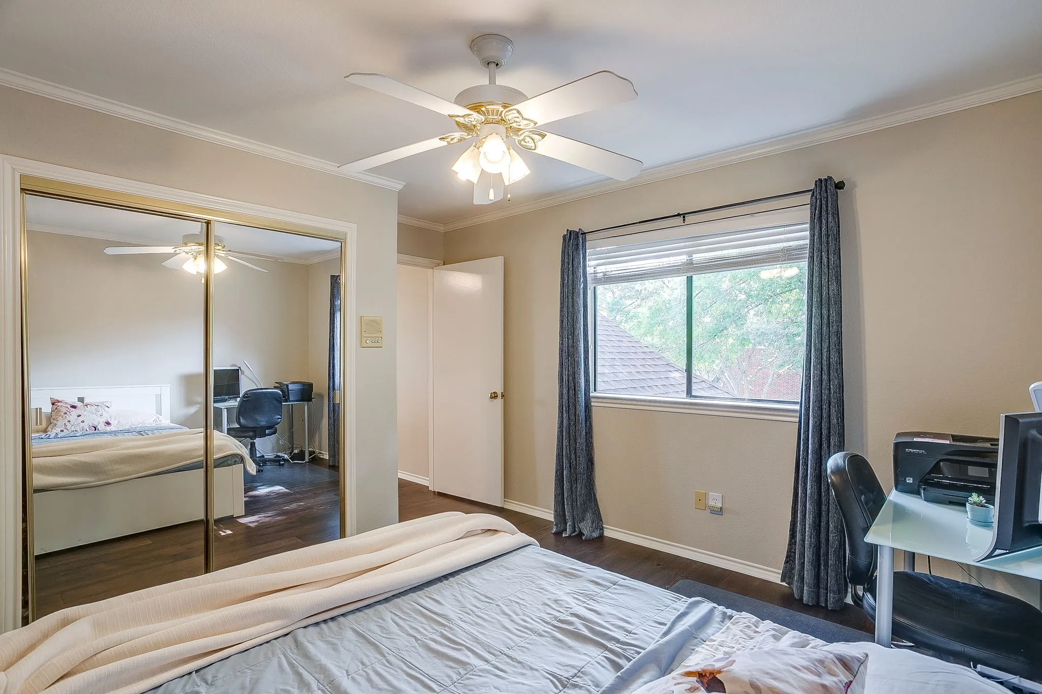 Bedroom featuring dark wood flooring, a ceiling fan with integrated lighting, a window with blinds, and mirrored closet doors
