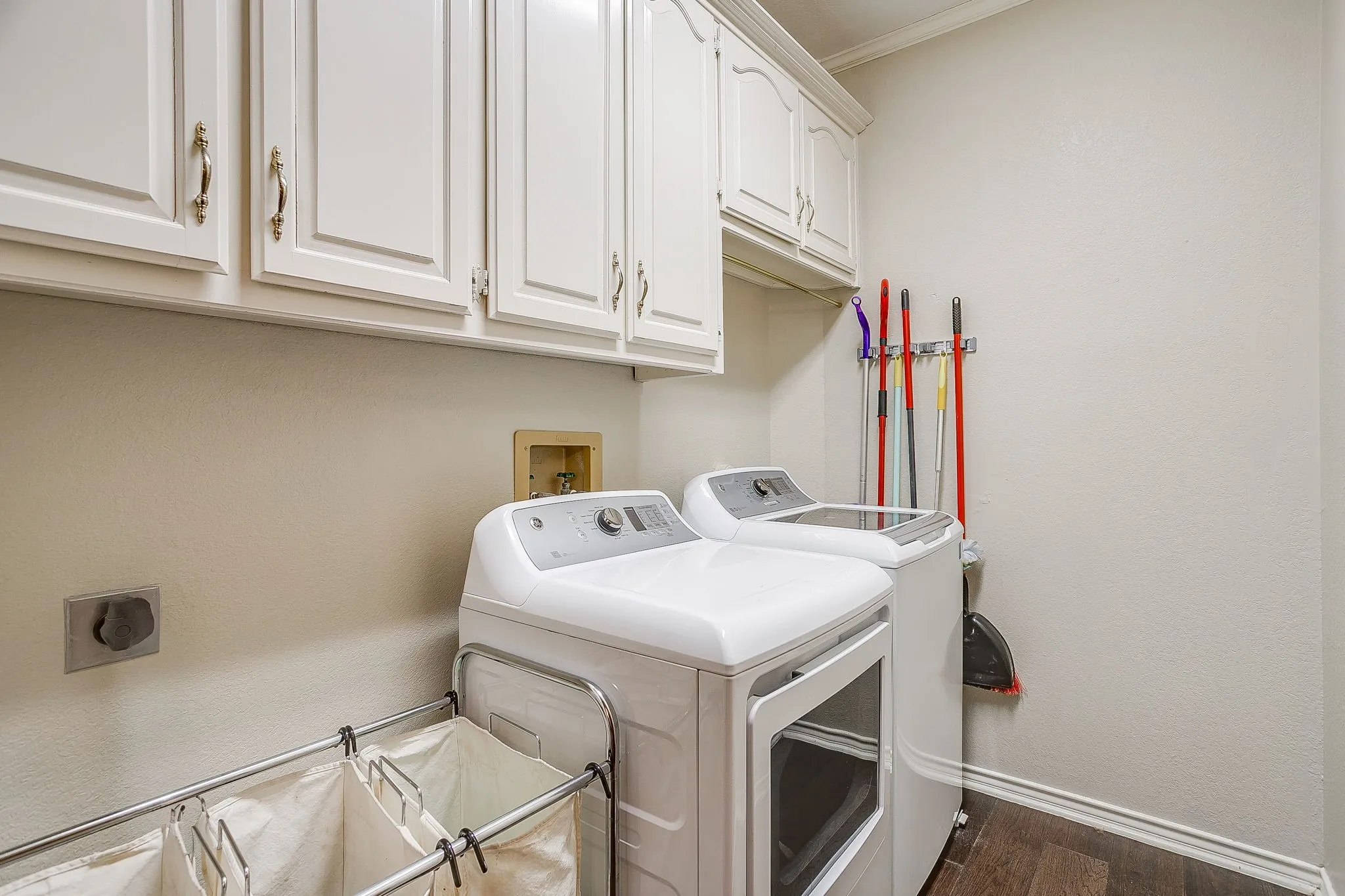 Dedicated utility space featuring white upper cabinetry and wood flooring