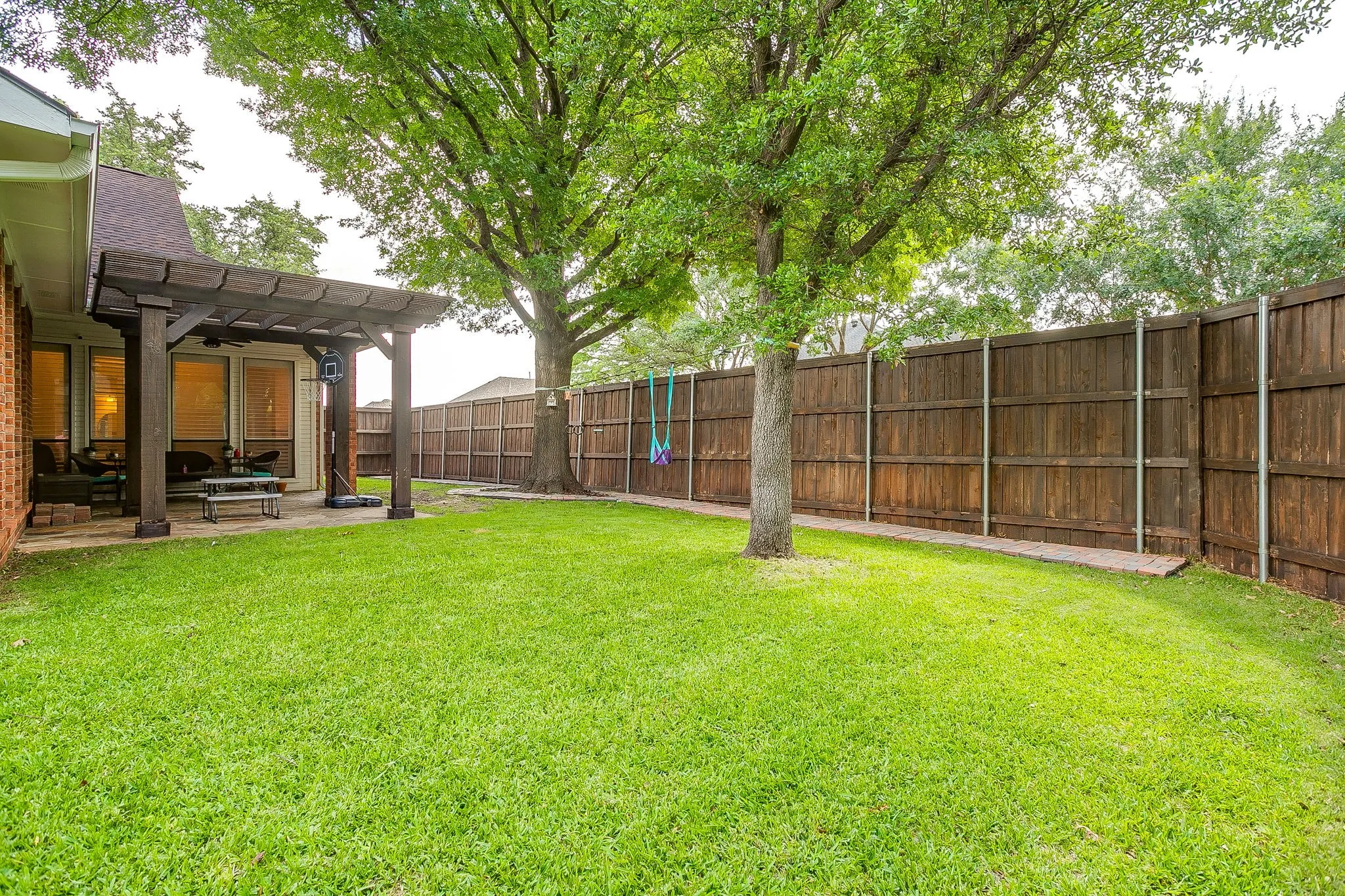 Backyard area featuring a wooden pergola-covered patio and a wooden privacy fence