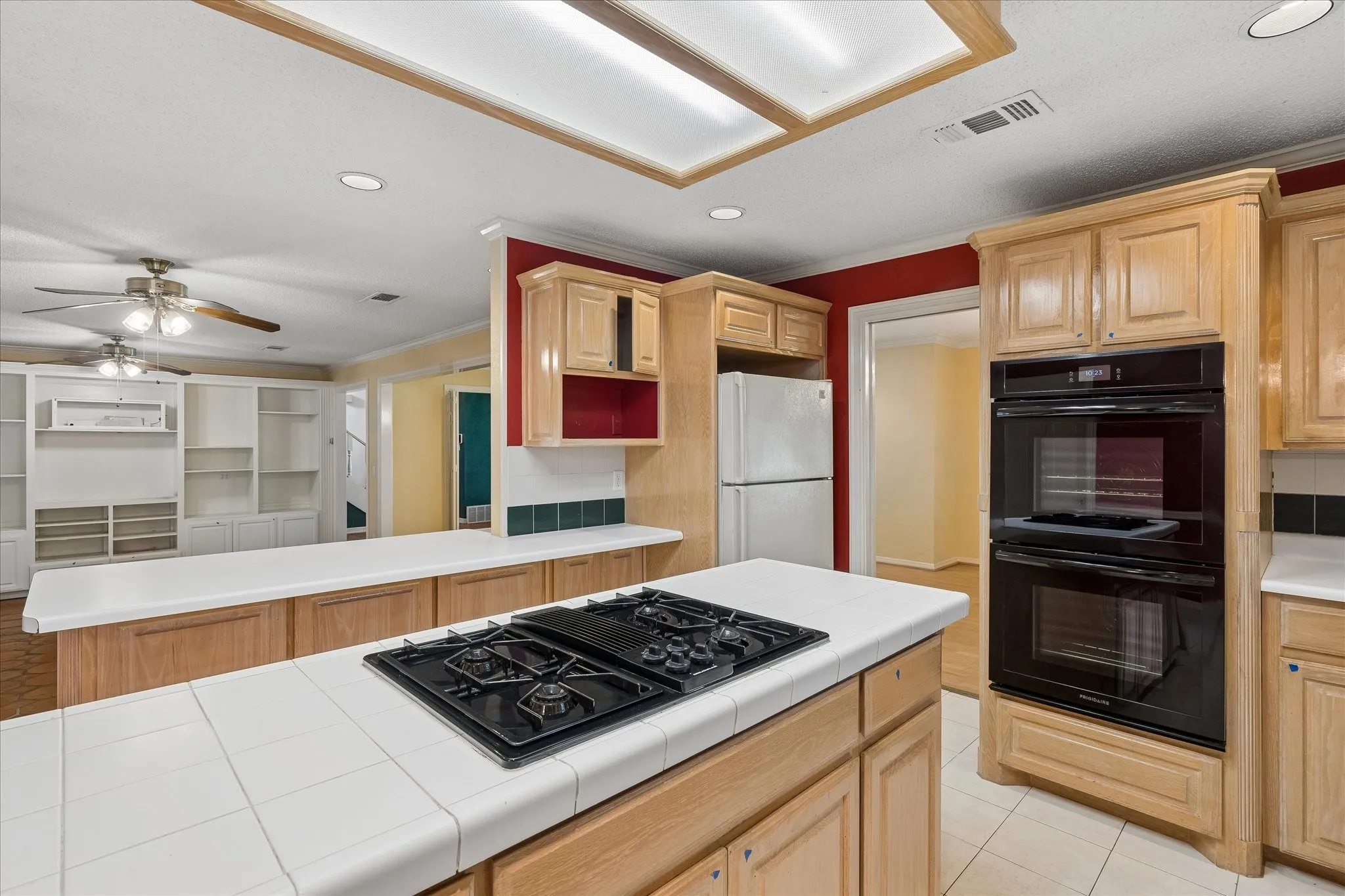 Kitchen featuring light wood cabinetry, white tile countertops, a black gas cooktop, and built-in double ovens