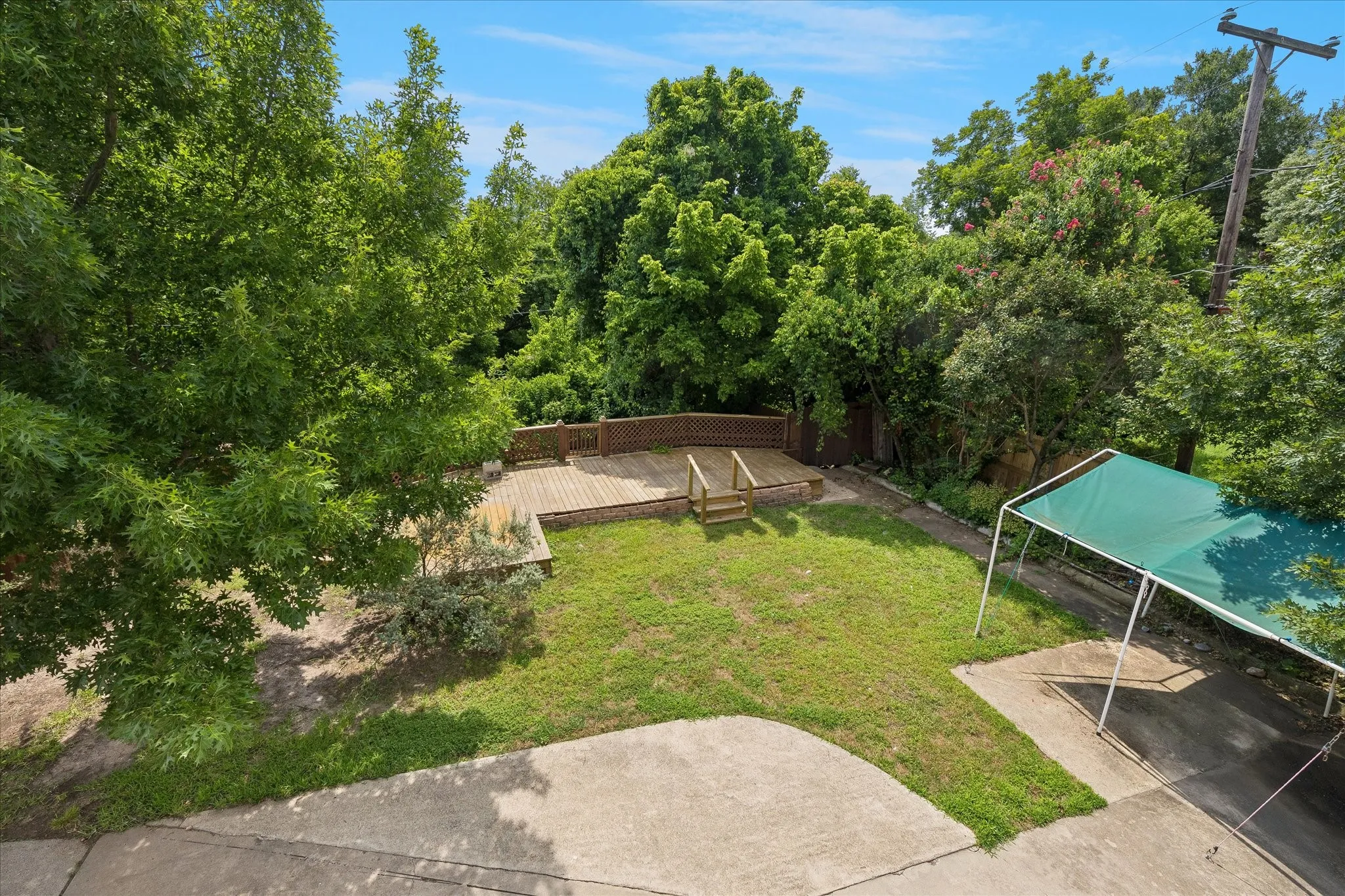 Expansive backyard featuring a multi-level wood deck, a concrete patio area, and a dedicated carport structure