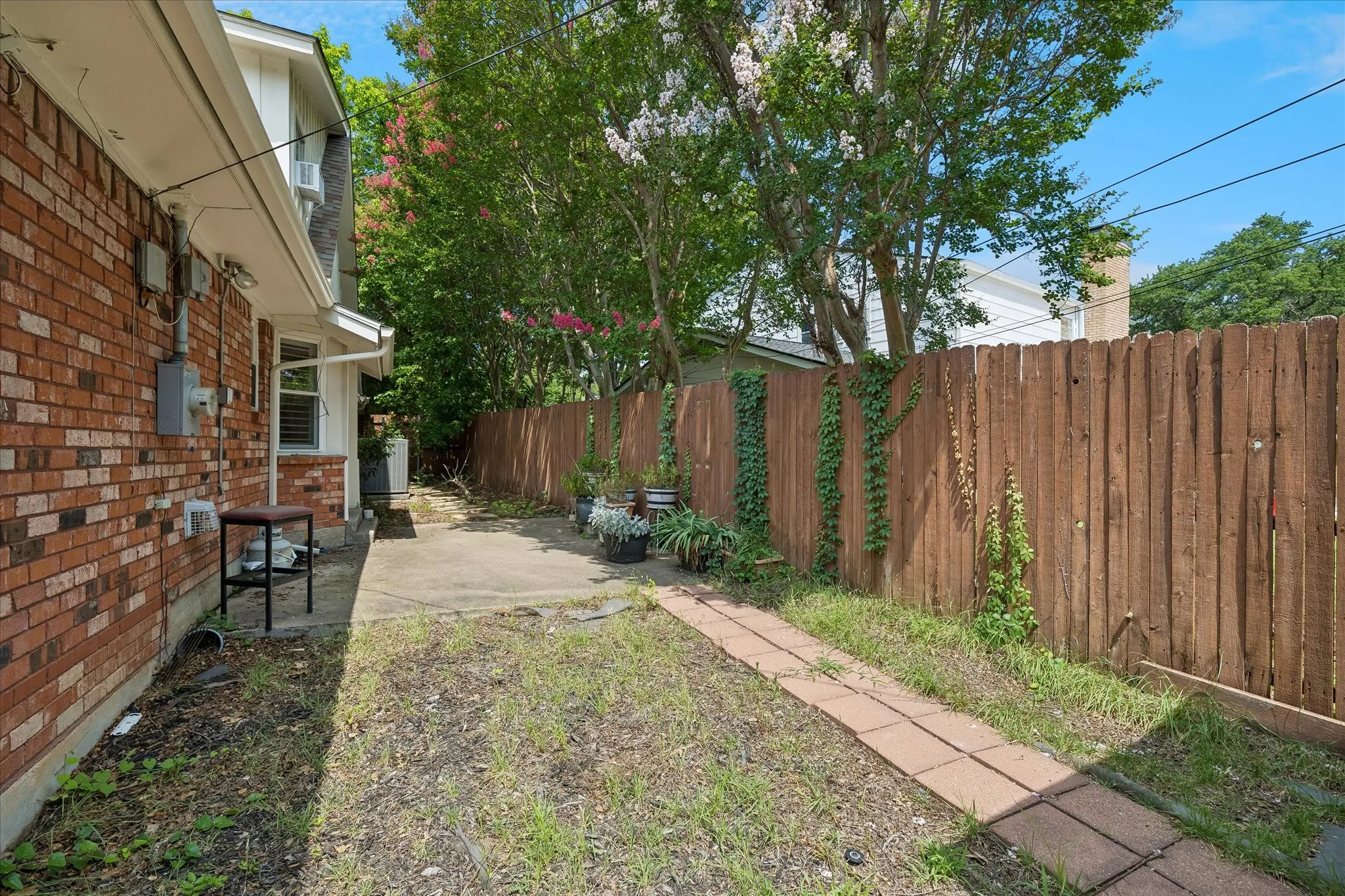 Private outdoor area featuring a concrete patio, a brick paver pathway, and a wood privacy fence