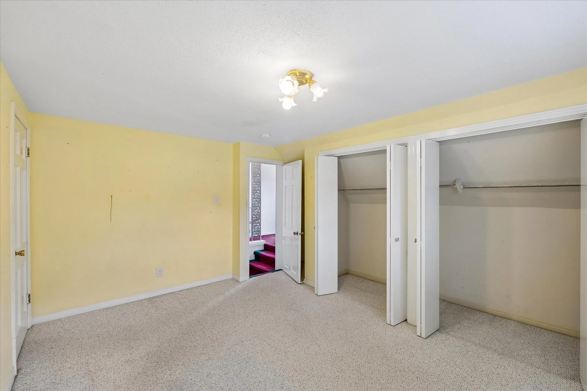 Carpeted room with multiple closet spaces, overhead lighting, and white trim