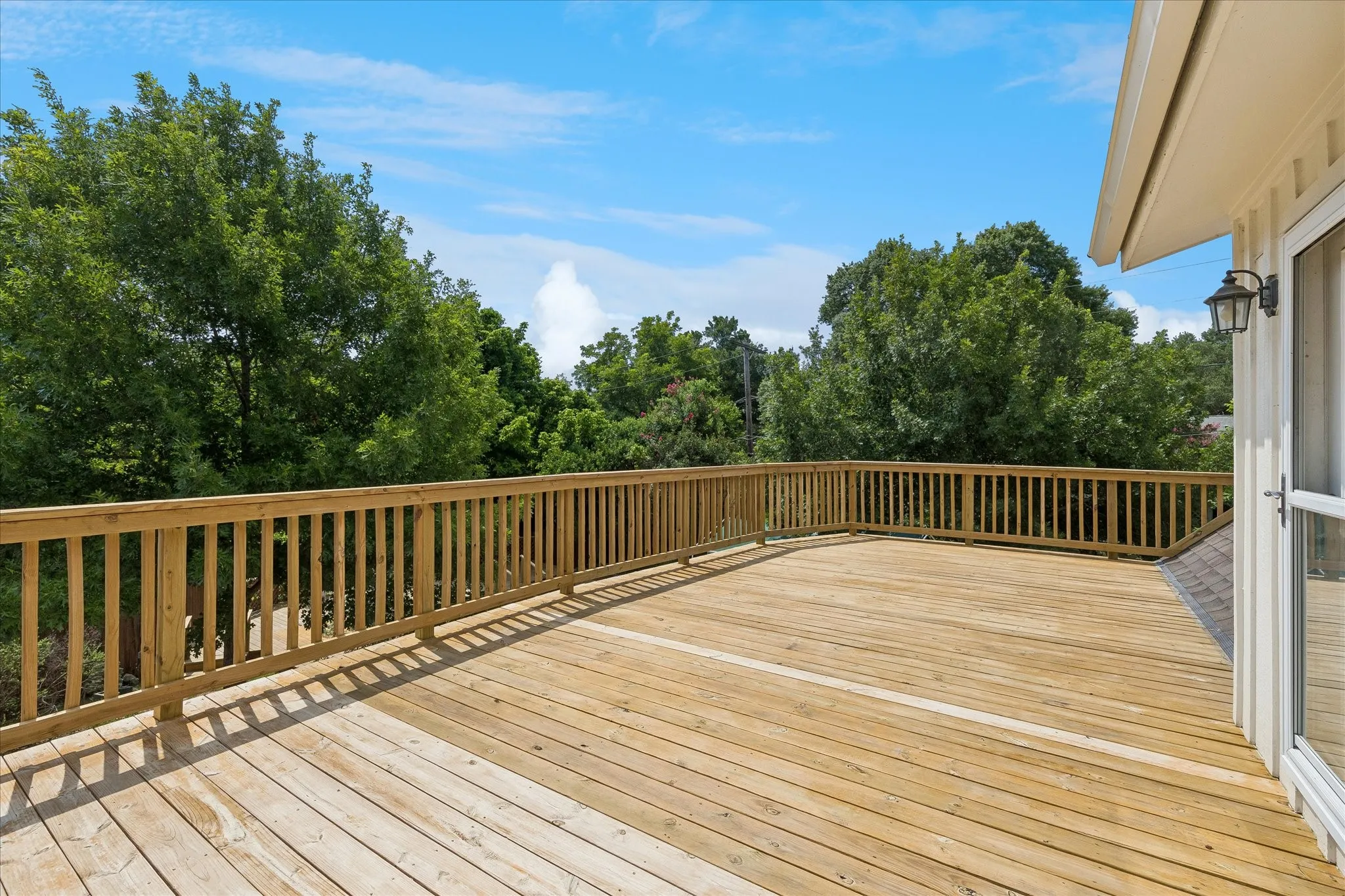 Expansive wood deck with natural wood railing, surrounded by mature trees