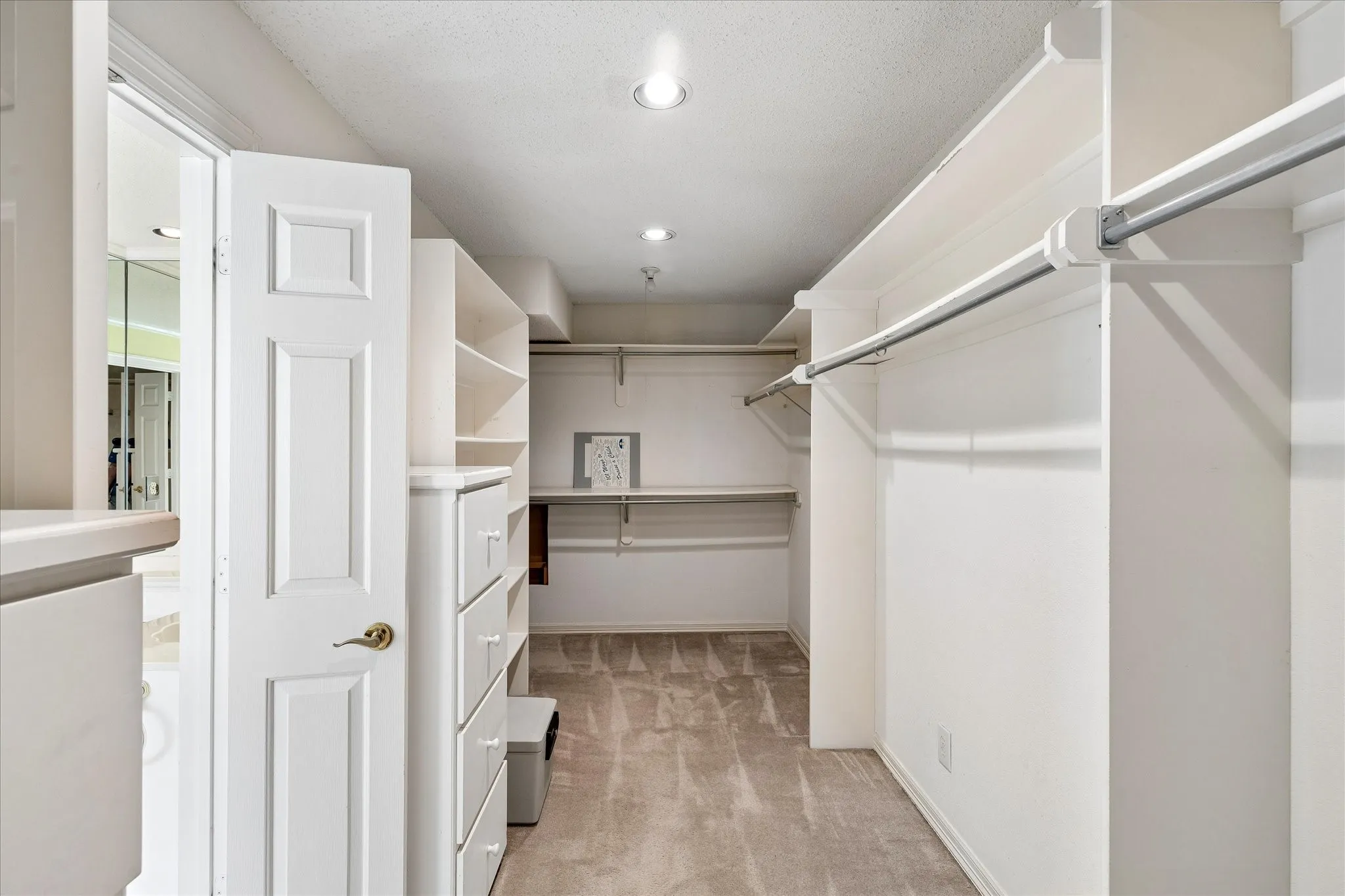 Expansive walk-in closet featuring built-in shelving, hanging rods, and integrated drawer storage