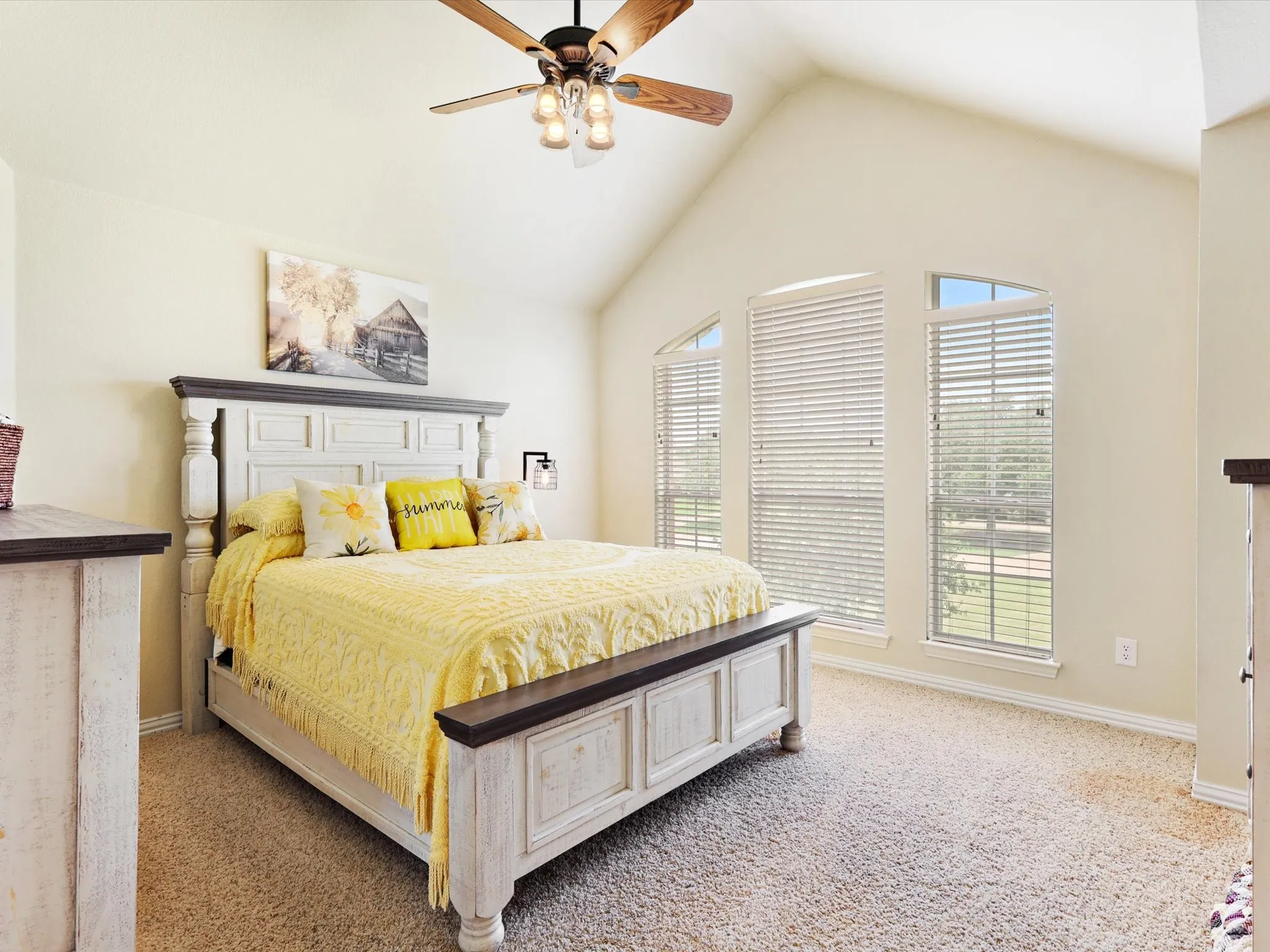 Room featuring a vaulted ceiling, ceiling fan with light fixture, and three large windows providing abundant natural light