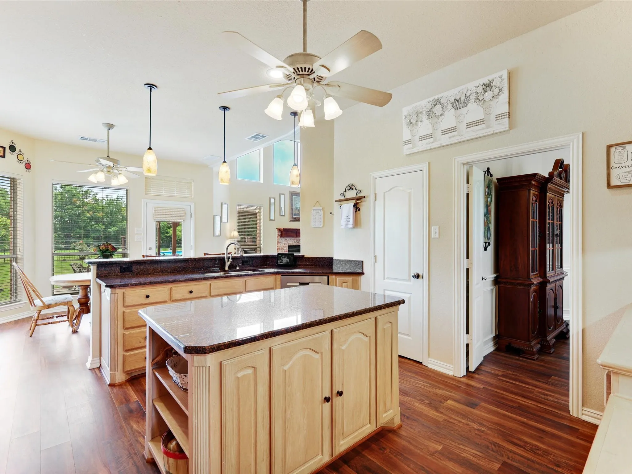 Kitchen featuring wood-finish flooring, a central island with a light-toned countertop, and perimeter cabinetry with a dark countertop