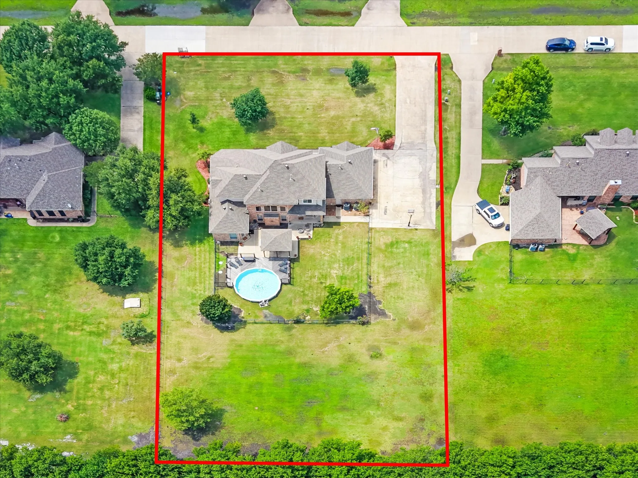 Expansive property featuring a multi-story residence with a rectangular pool, substantial green space, an extended driveway, and mature trees