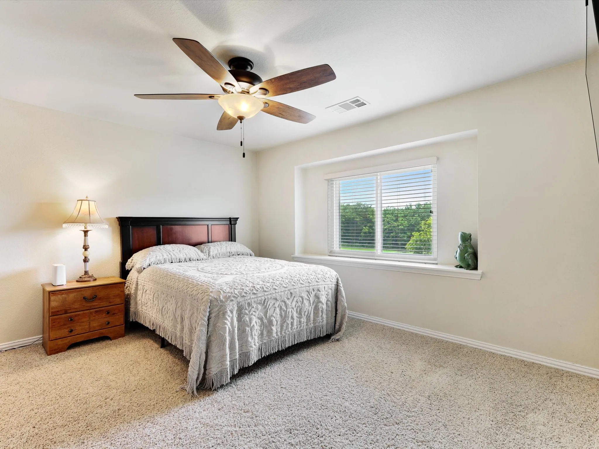 Carpeted bedroom featuring a ceiling fan, a window with horizontal blinds, and neutral wall tones