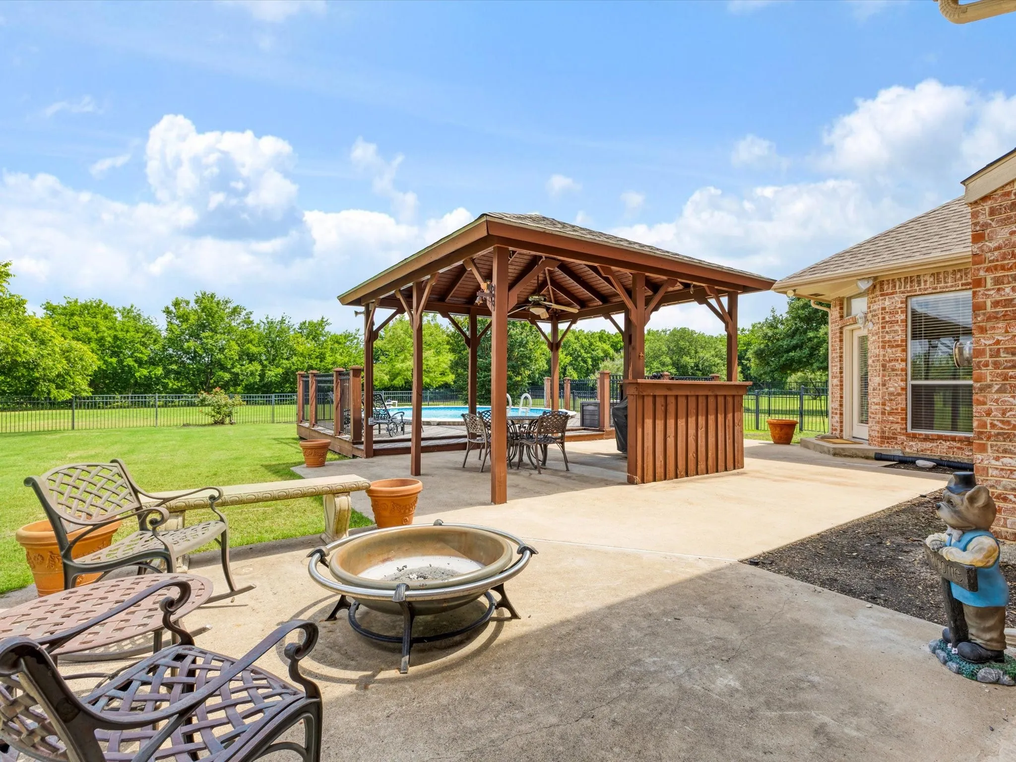 Spacious concrete patio featuring a wood-frame gazebo, built-in bar, and a dedicated fire pit area