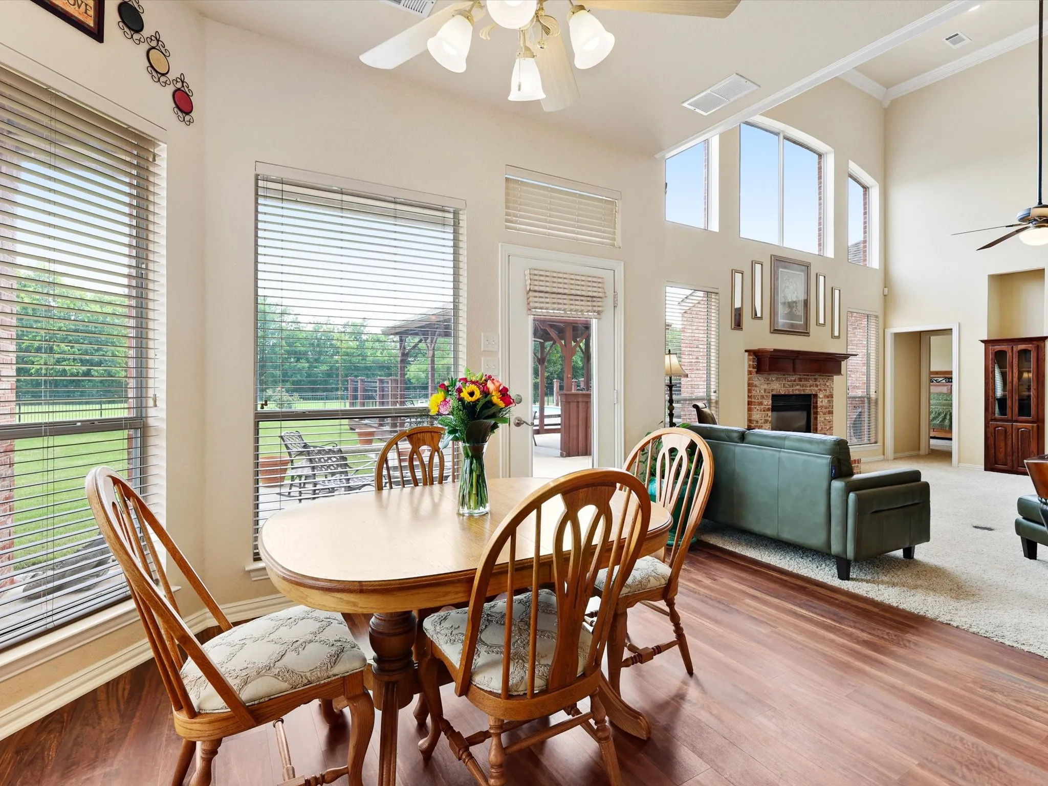Open-concept living space featuring wood-finish flooring, a two-story vaulted ceiling, and ample natural light from multiple windows