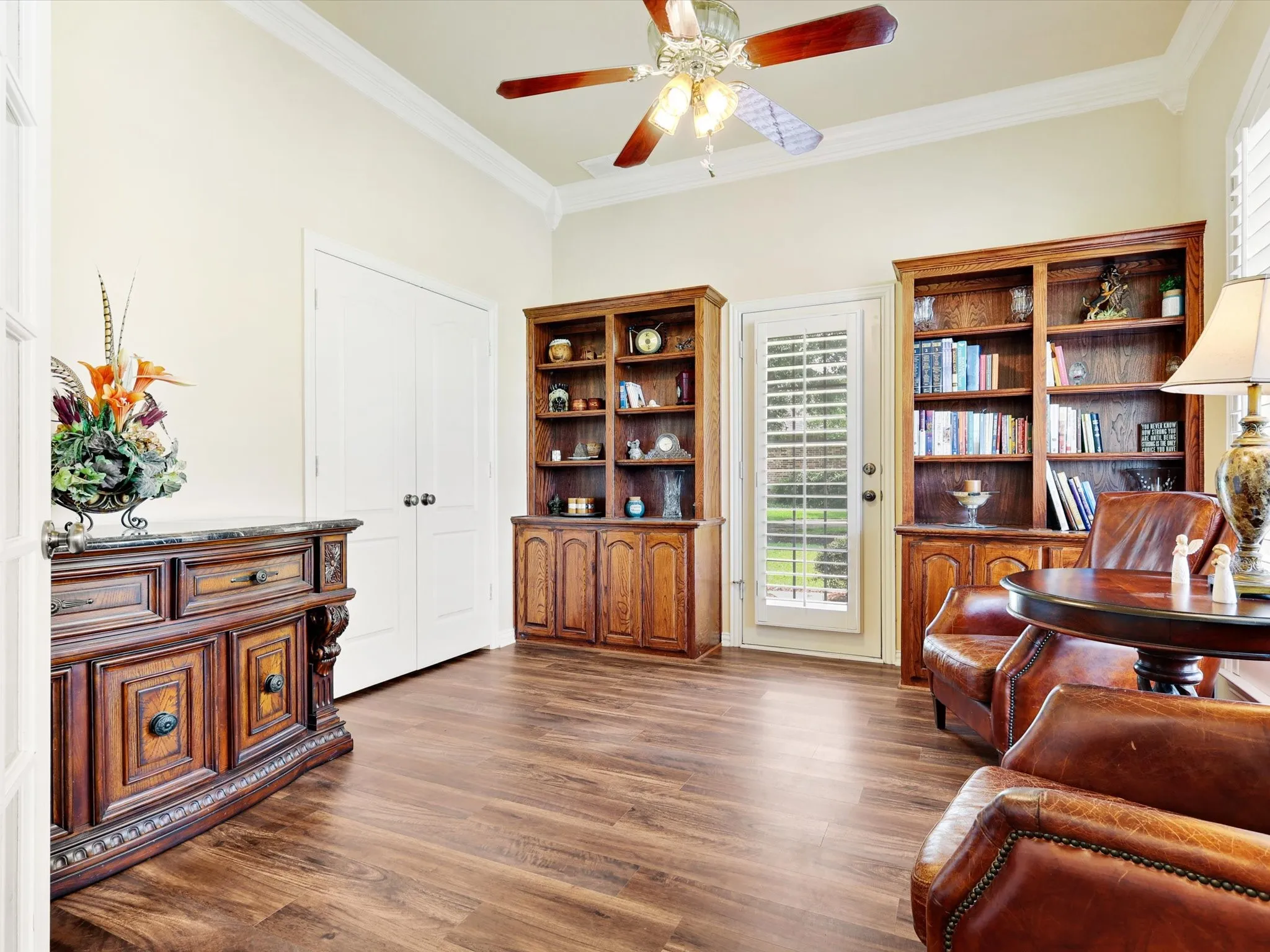 Room featuring wood-finish flooring, crown molding, and a ceiling fan