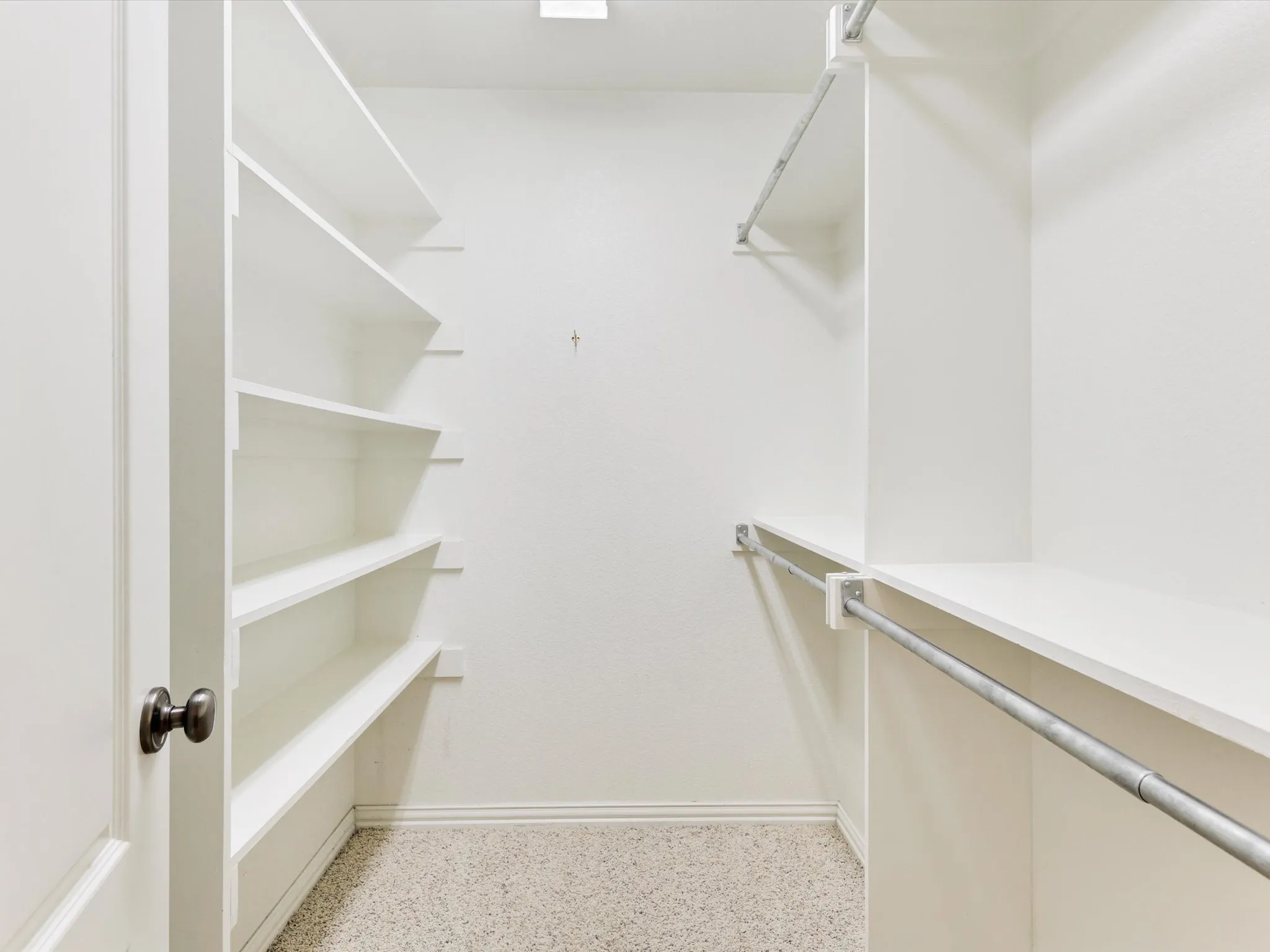 Walk-in closet featuring built-in shelving, two hanging rods, and light-toned flooring