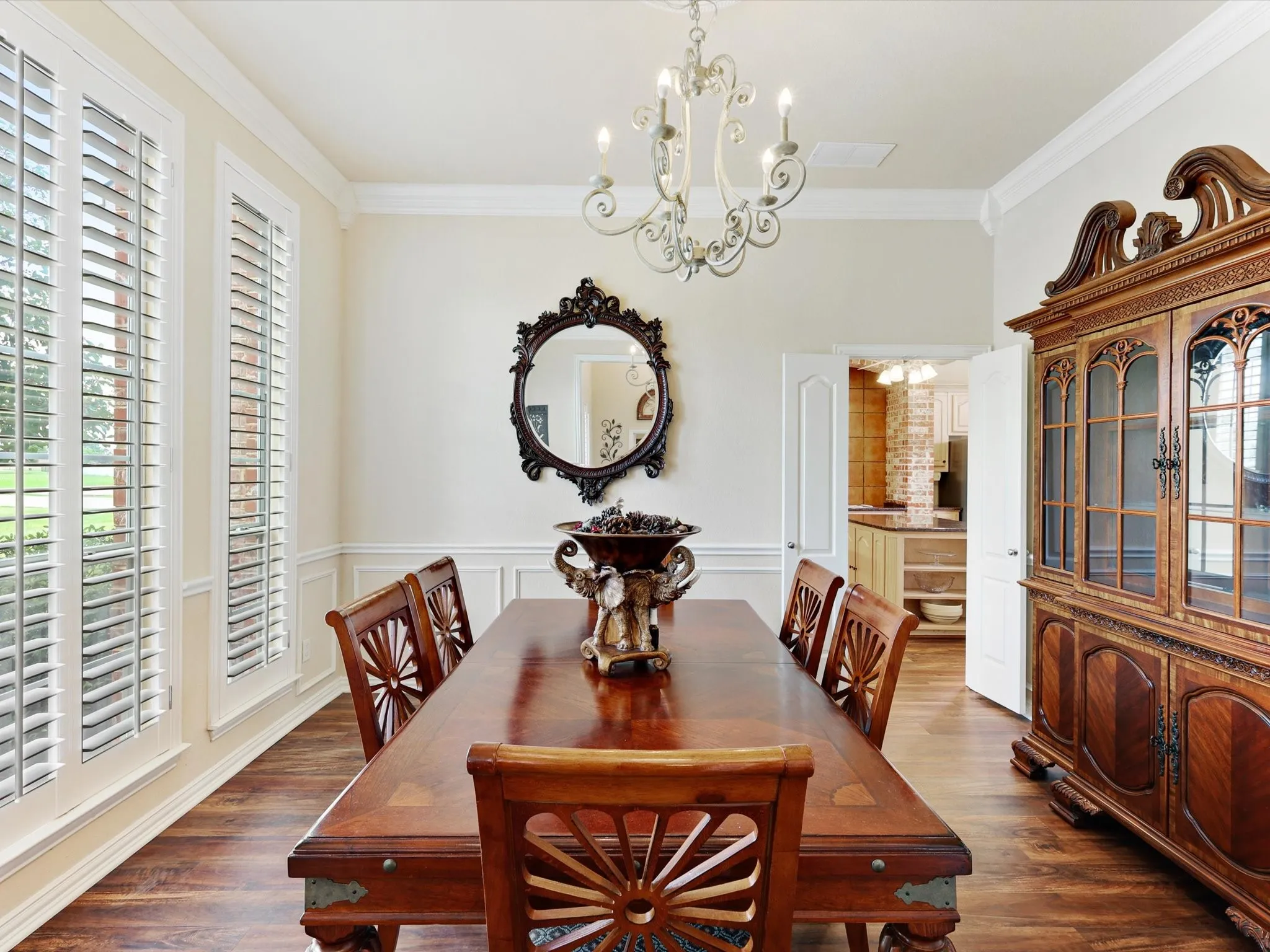 Elegant dining area featuring wood-finish flooring, wainscoting, and crown molding