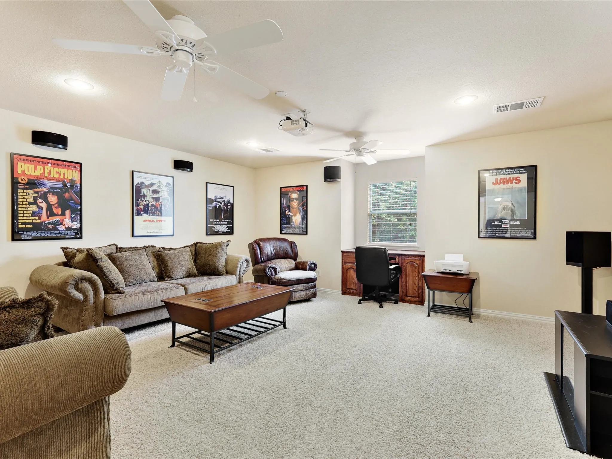 Spacious carpeted room featuring recessed lighting, multiple ceiling fans, and a built-in desk with wood cabinetry