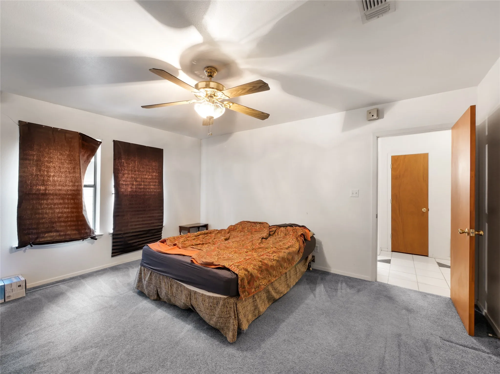 Spacious room featuring light gray carpeting, a ceiling fan with integrated lighting, and two windows