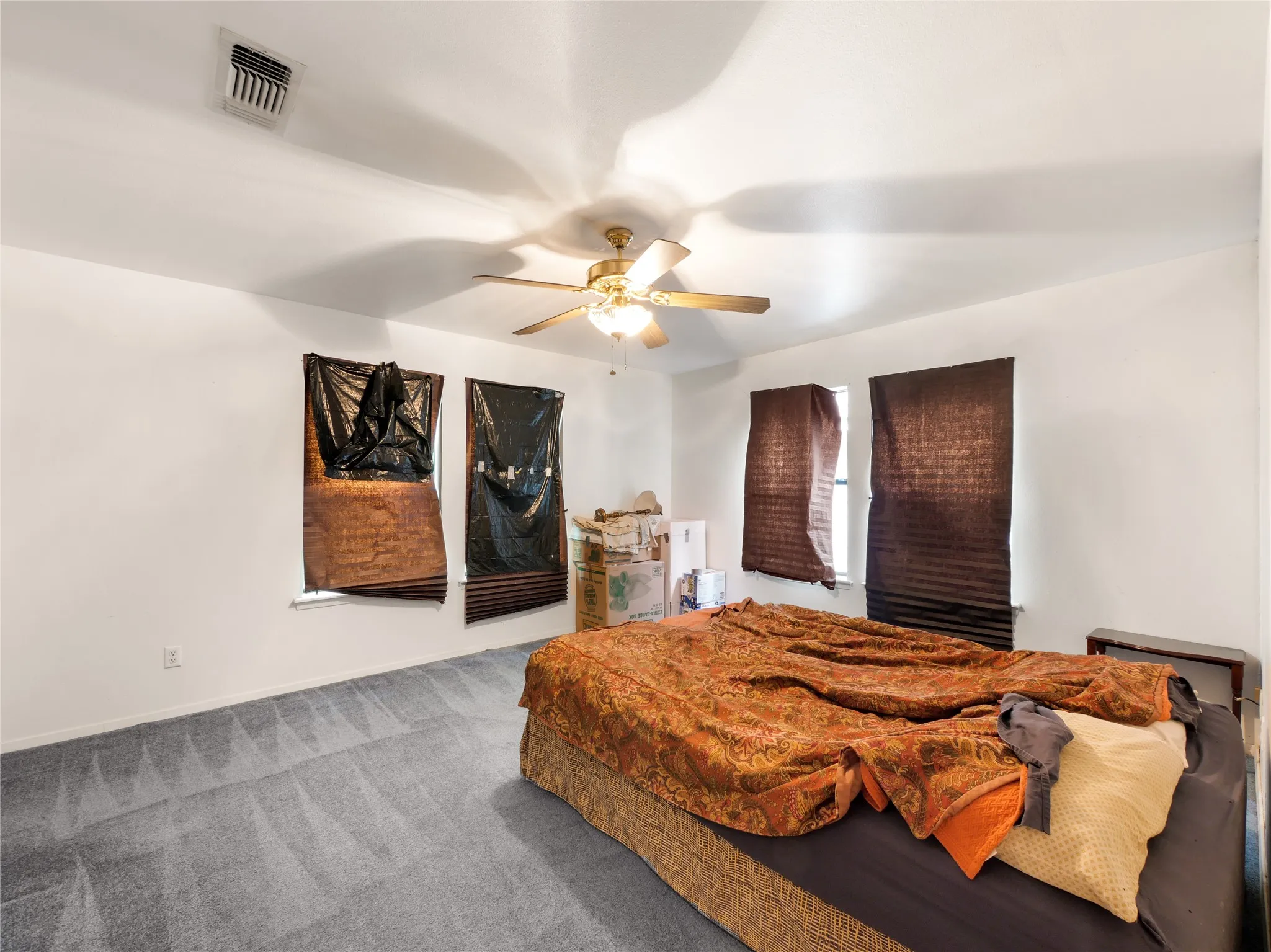 Spacious room featuring light gray carpet, white walls, and a ceiling fan with integrated lighting