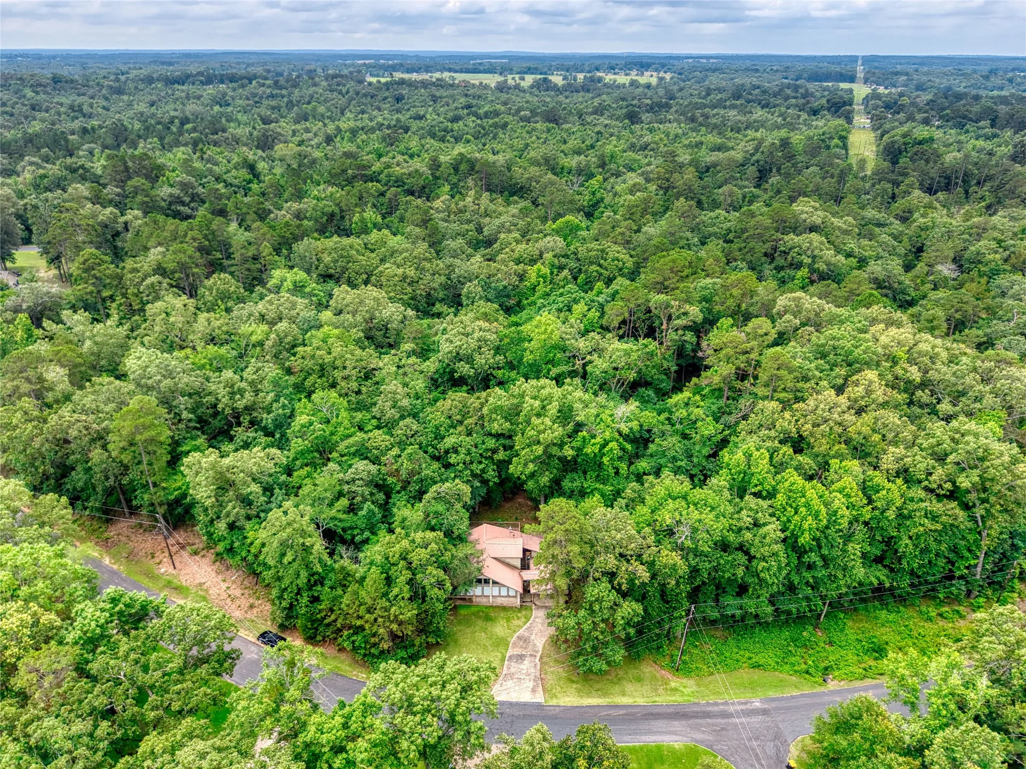 Aerial perspective highlighting a property nestled within extensive mature tree coverage