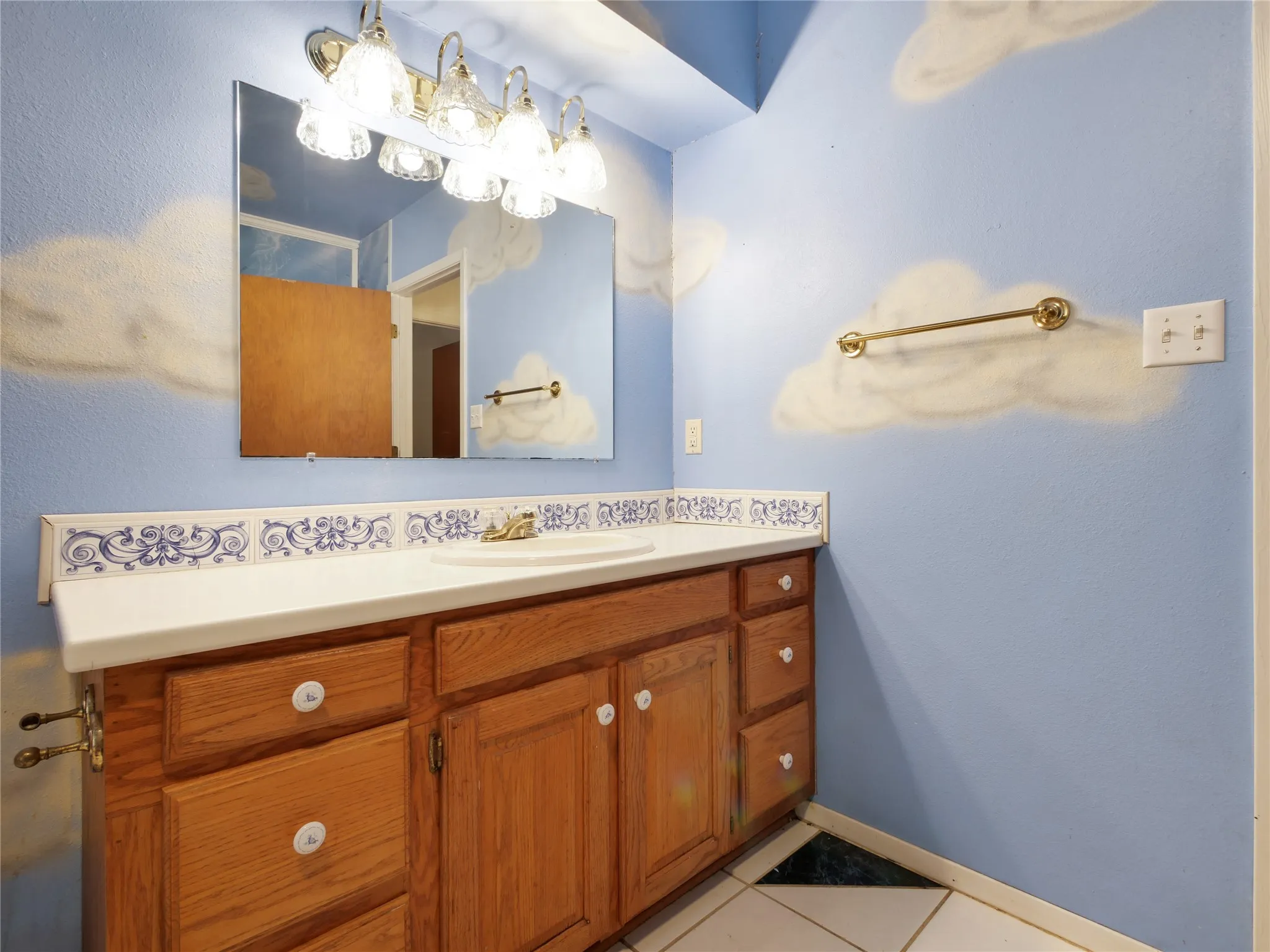 Bathroom vanity featuring a single basin, white countertop, and wood-finish cabinetry
