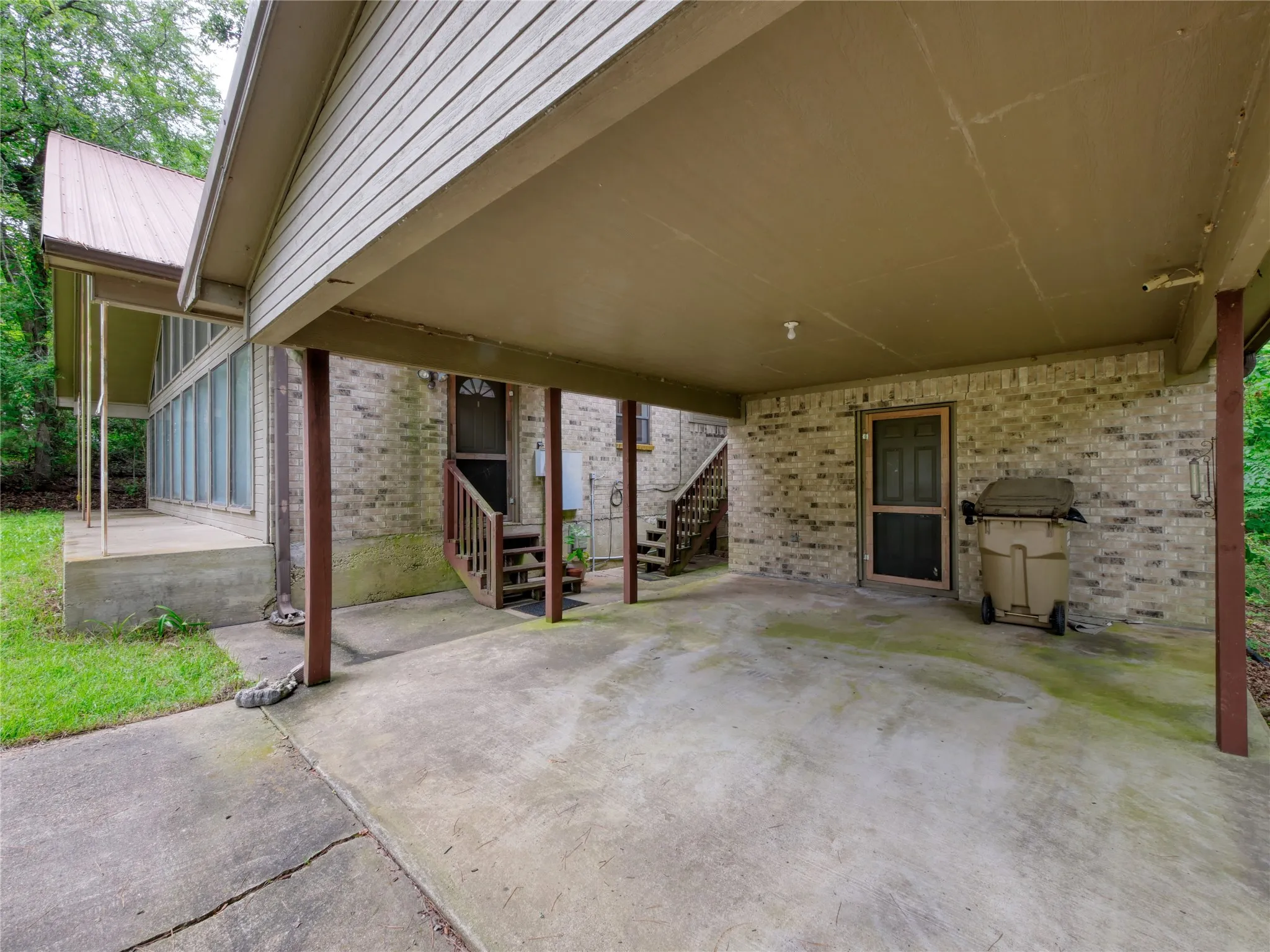 Covered concrete carport with brick exterior walls and two entry doors