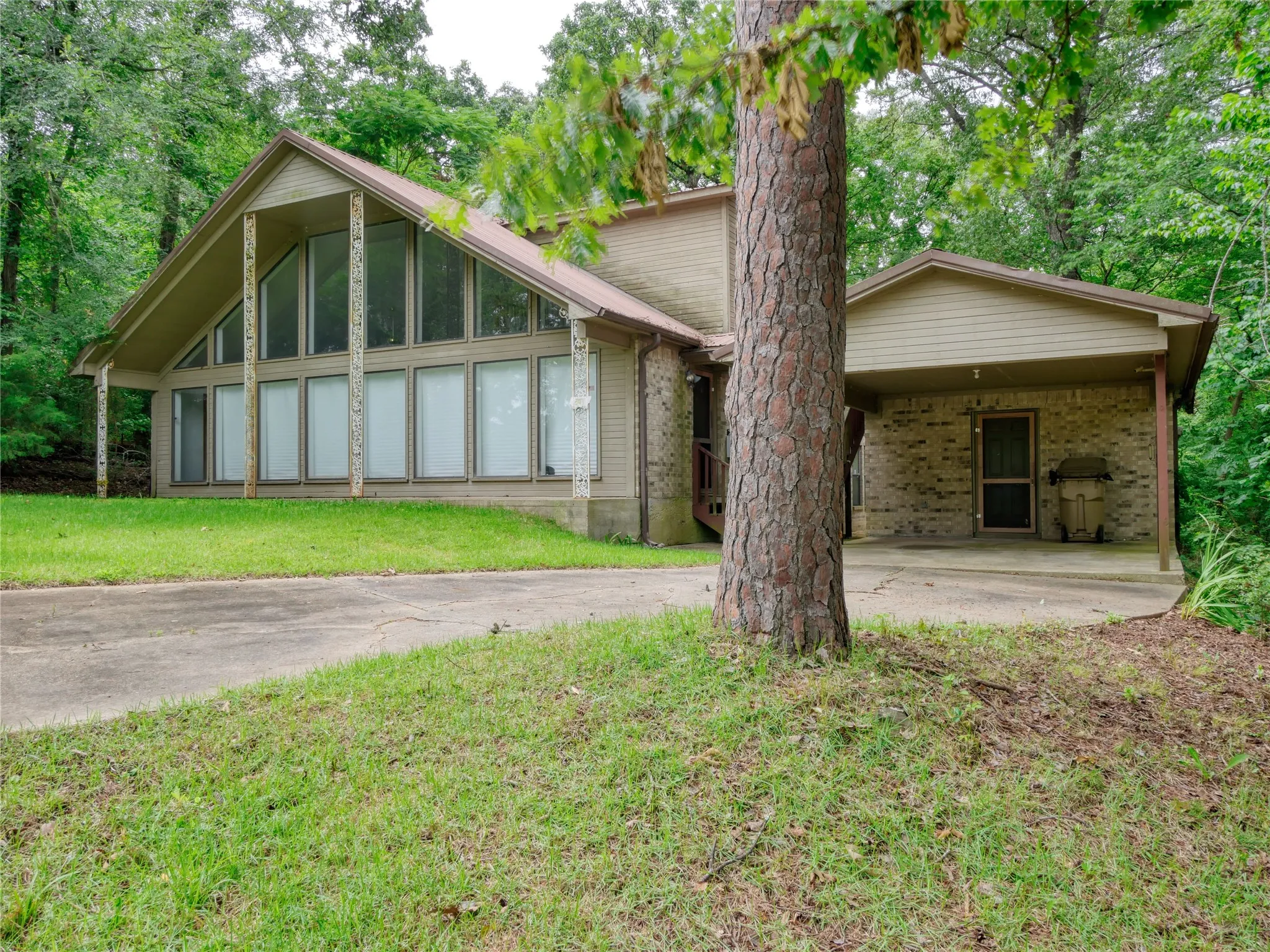 Contemporary A-frame residence featuring an expansive window wall and a covered carport