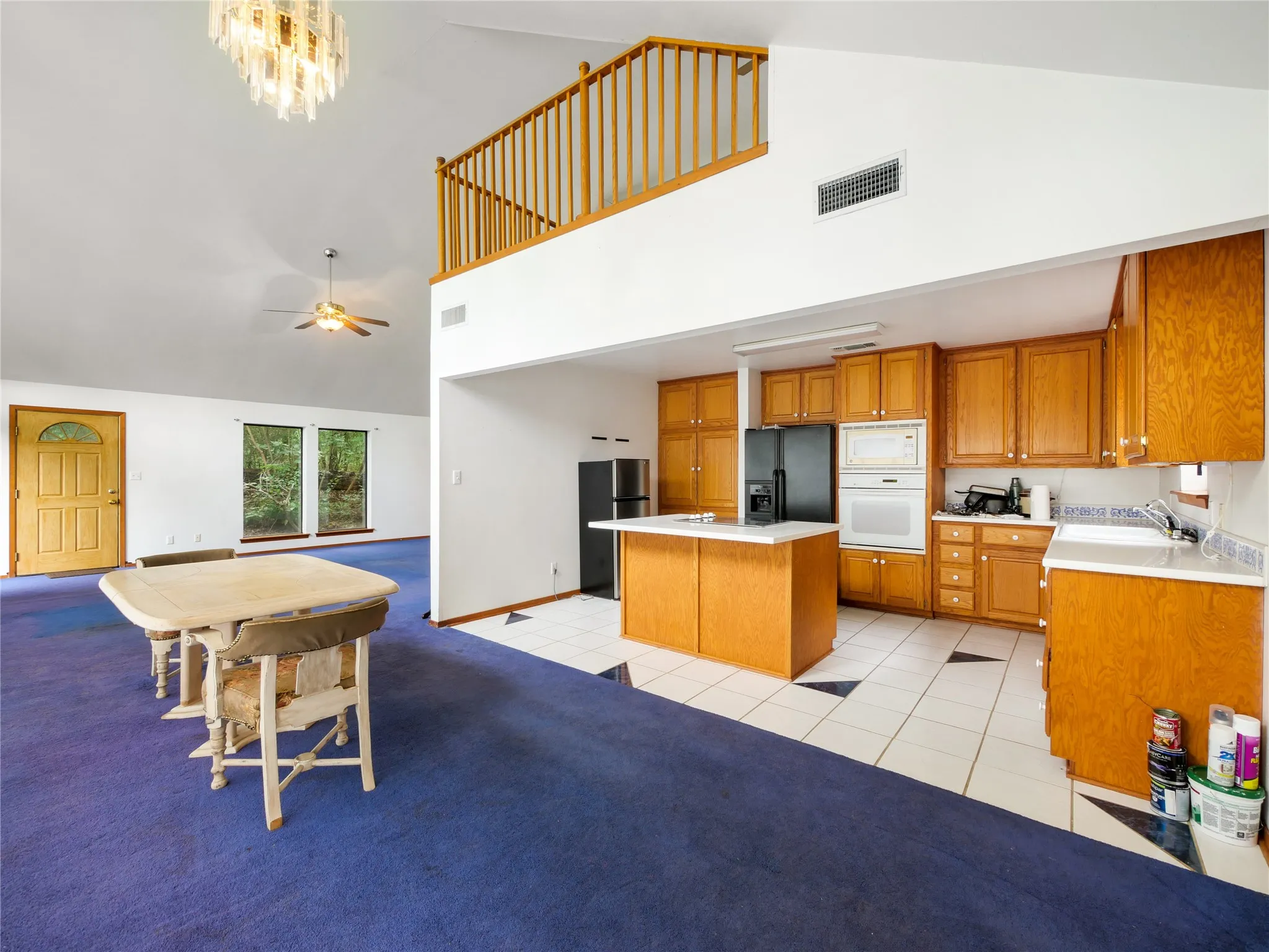 Open-concept living space featuring a vaulted ceiling and a loft area with wood railing