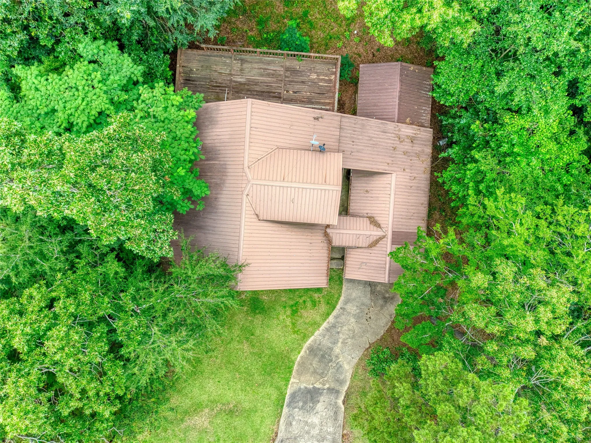 Architectural roofline featuring multiple gables and a neutral tone, set amidst mature, verdant trees