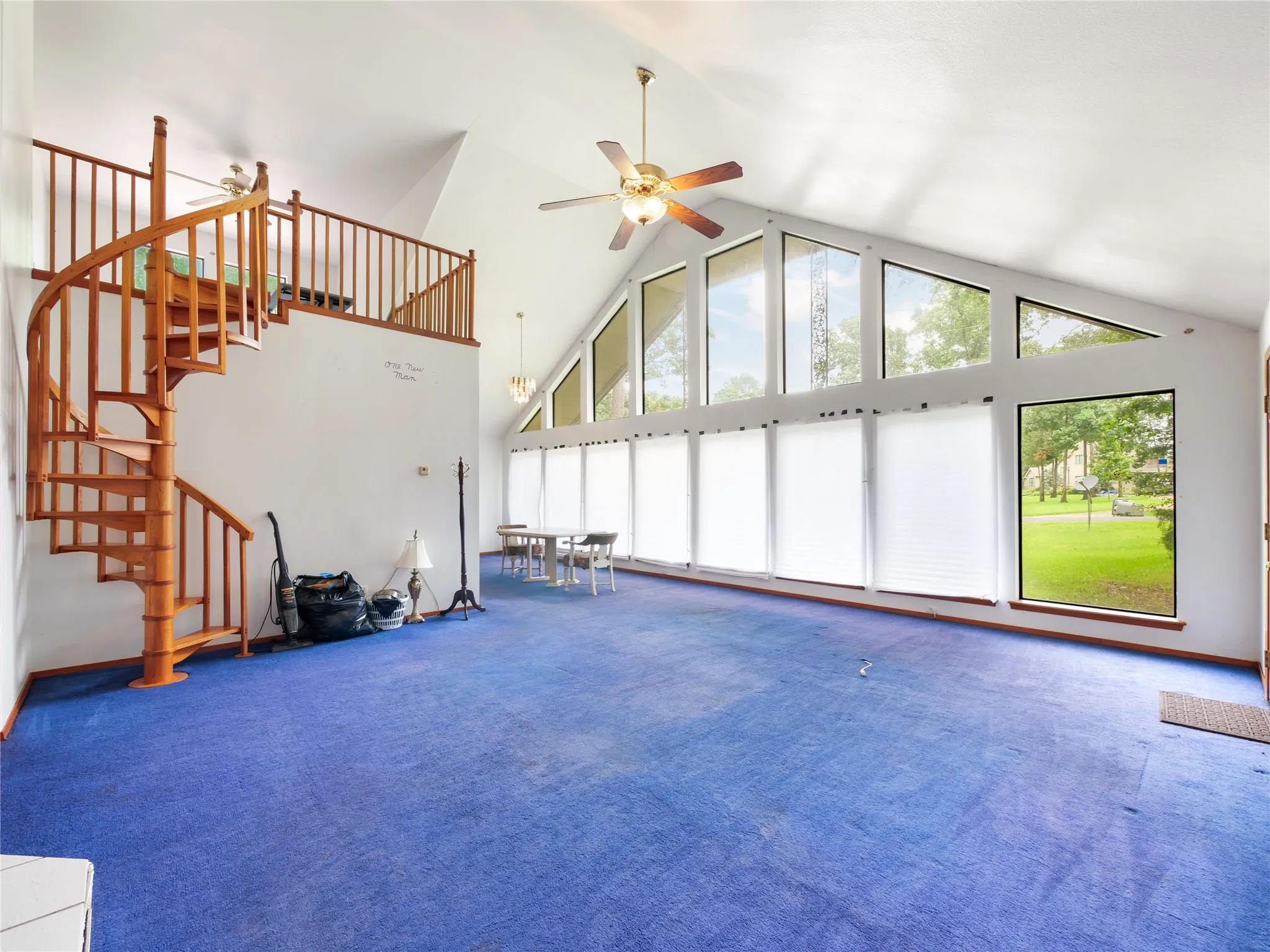 Spacious interior featuring a spiral staircase, vaulted ceilings, and a wall of windows