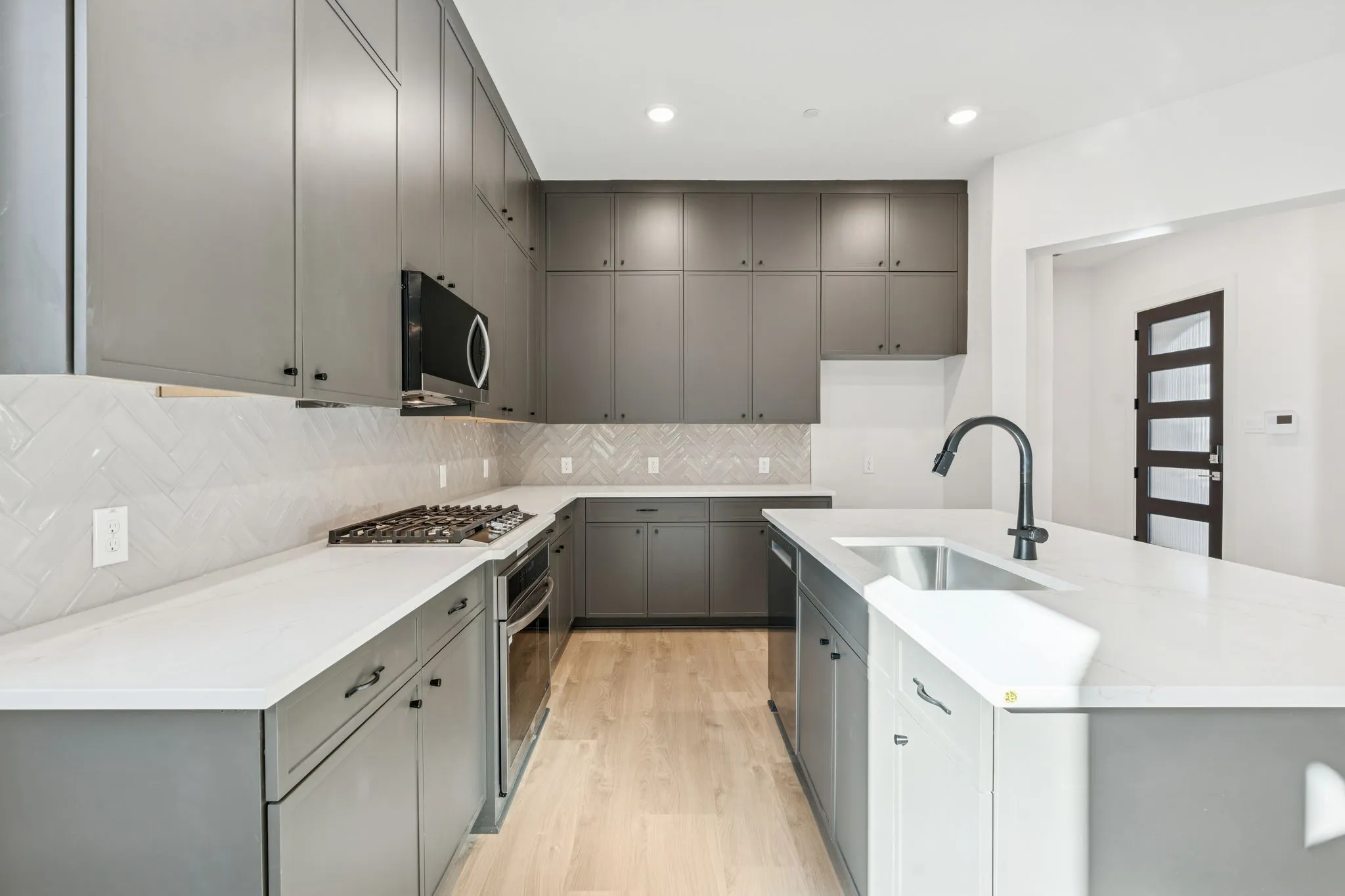 Quartz countertops, gas burner cooktop and black accent hardware.