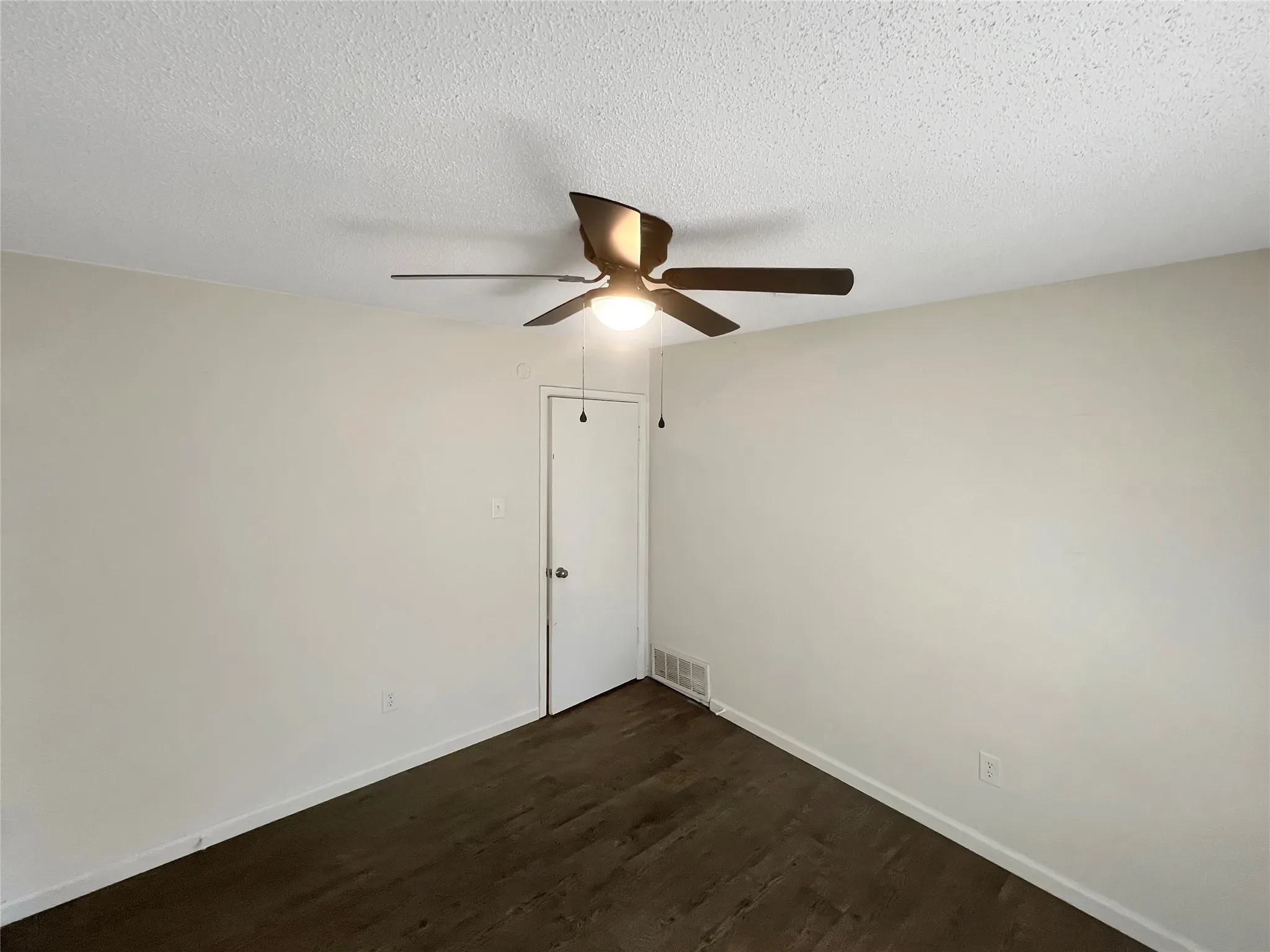 Room featuring neutral wall tones, wood-finish flooring, and a ceiling fan with integrated lighting