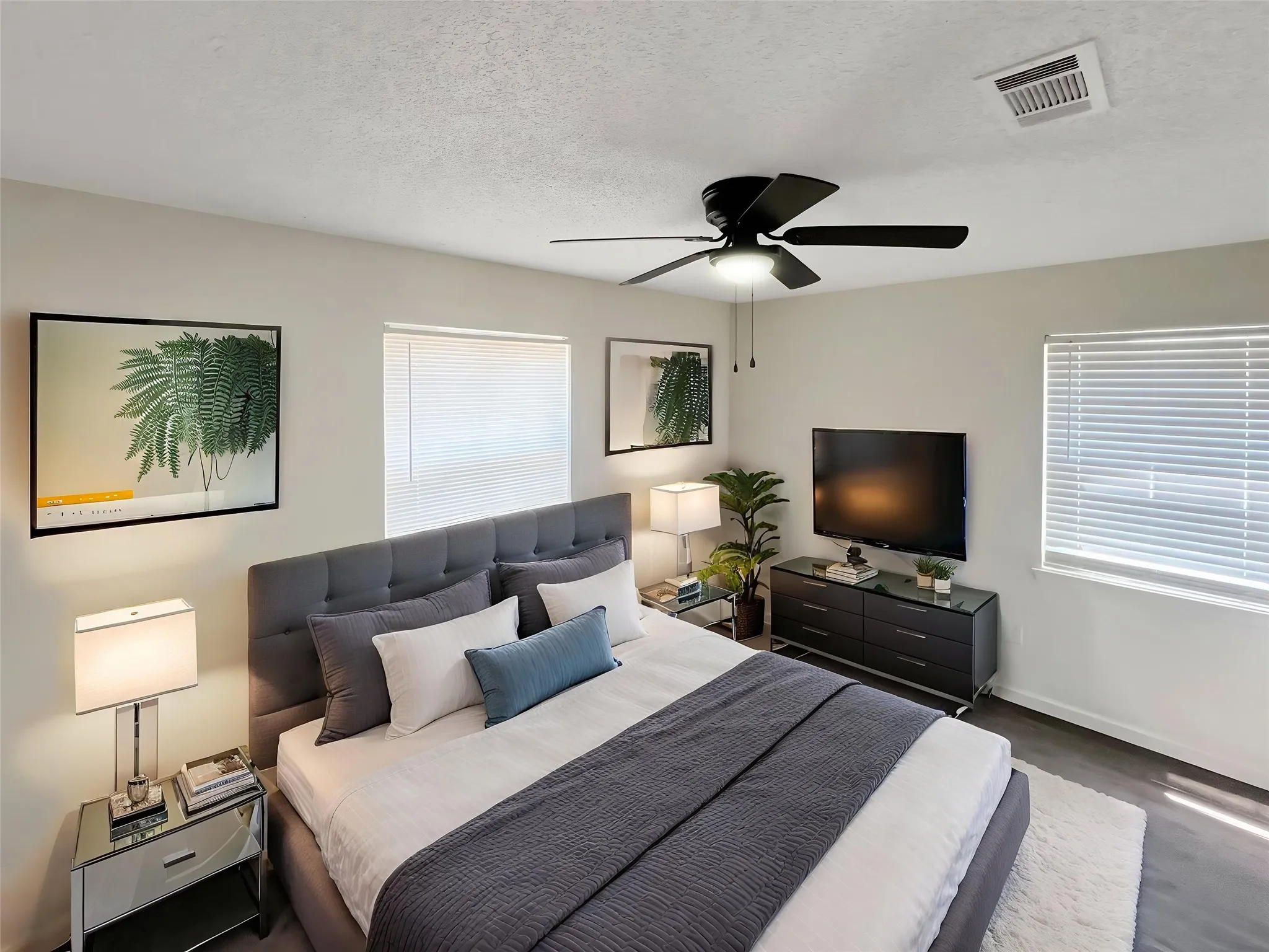 Virtually staged - Spacious bedroom featuring wood-finish flooring, multiple windows with blinds, and a ceiling fan