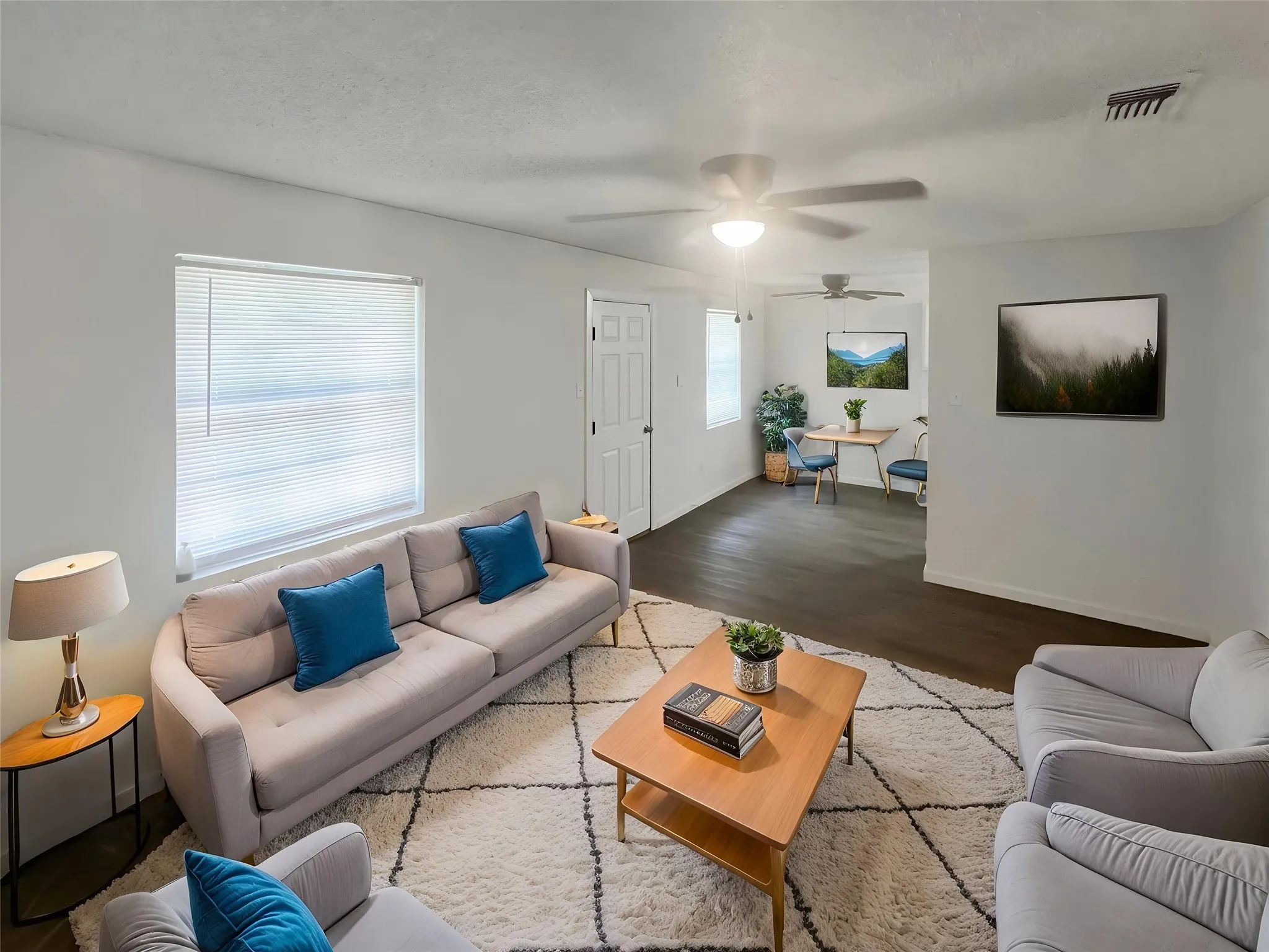 Virtually staged - Living area featuring a spacious layout with white walls and dark wood-finish flooring