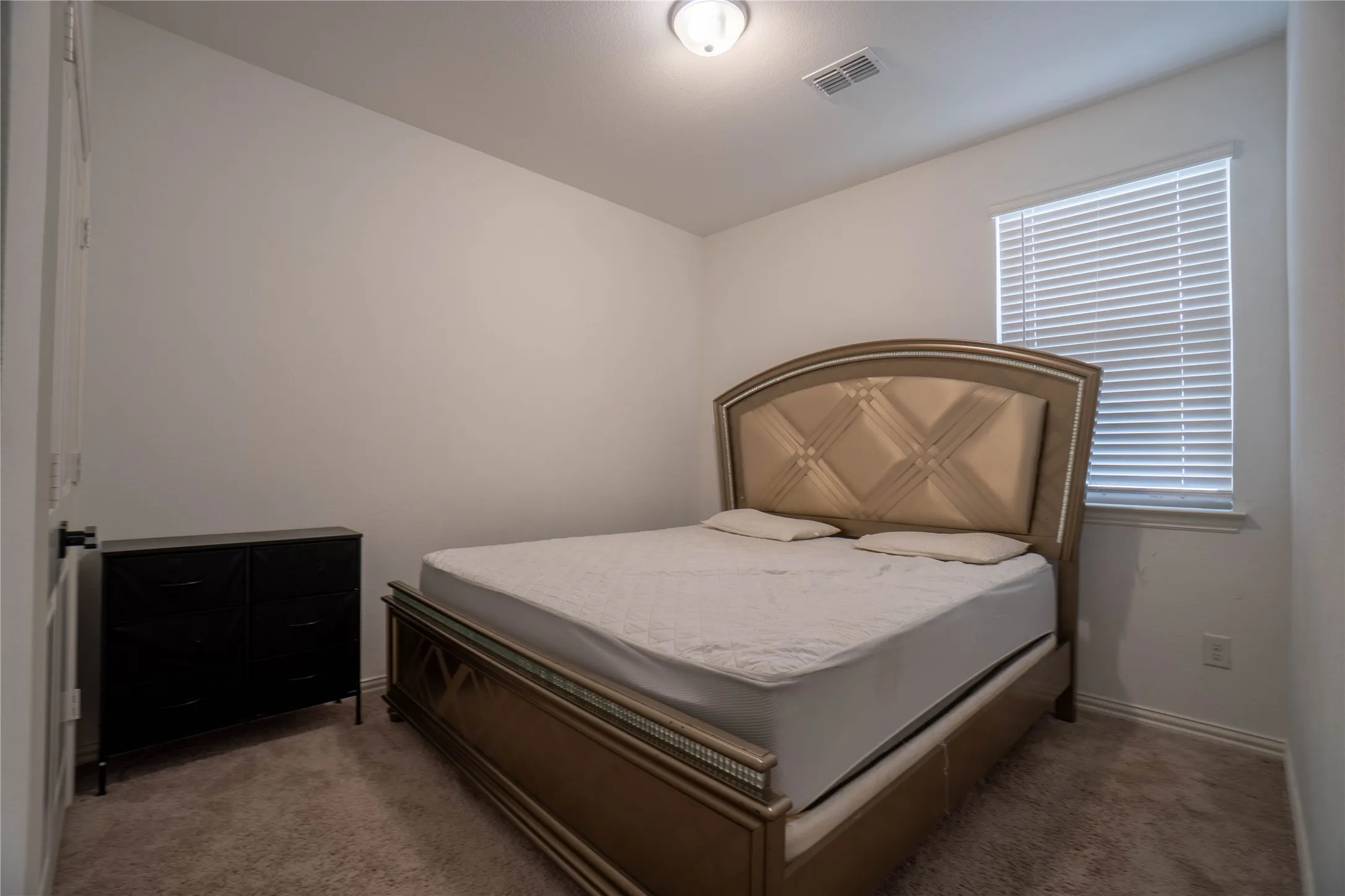 Carpeted room with a ceiling-mounted light fixture, a window with horizontal blinds, and baseboard trim