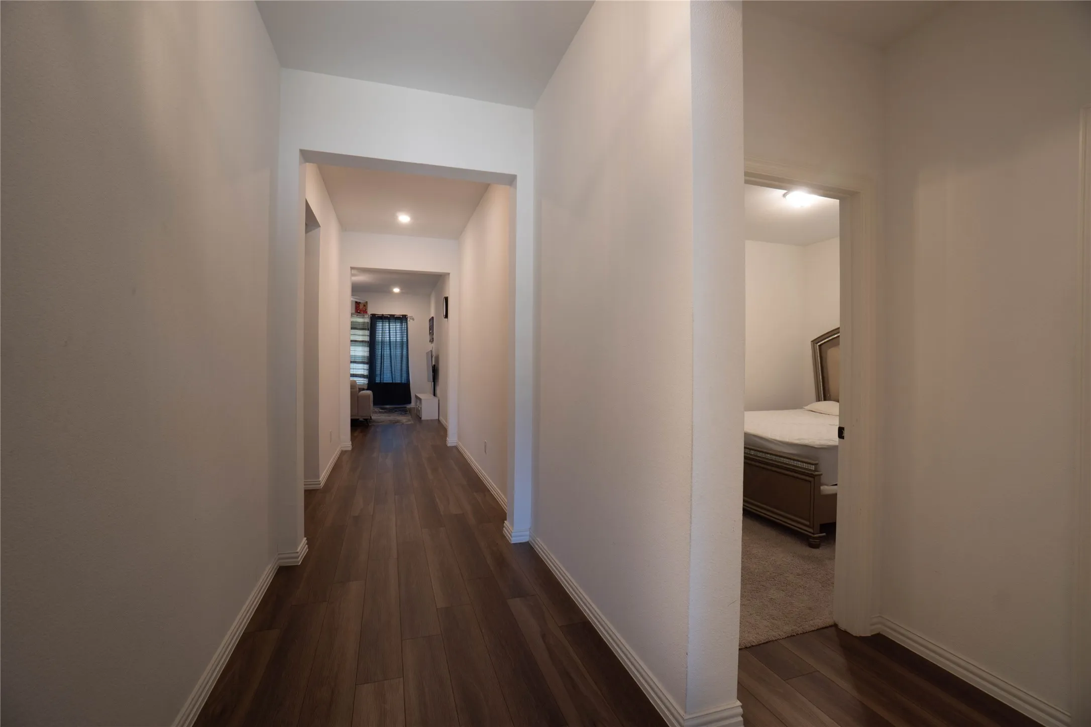 Hallway featuring wood-finish flooring, white baseboards, recessed lighting, and a neutral color palette