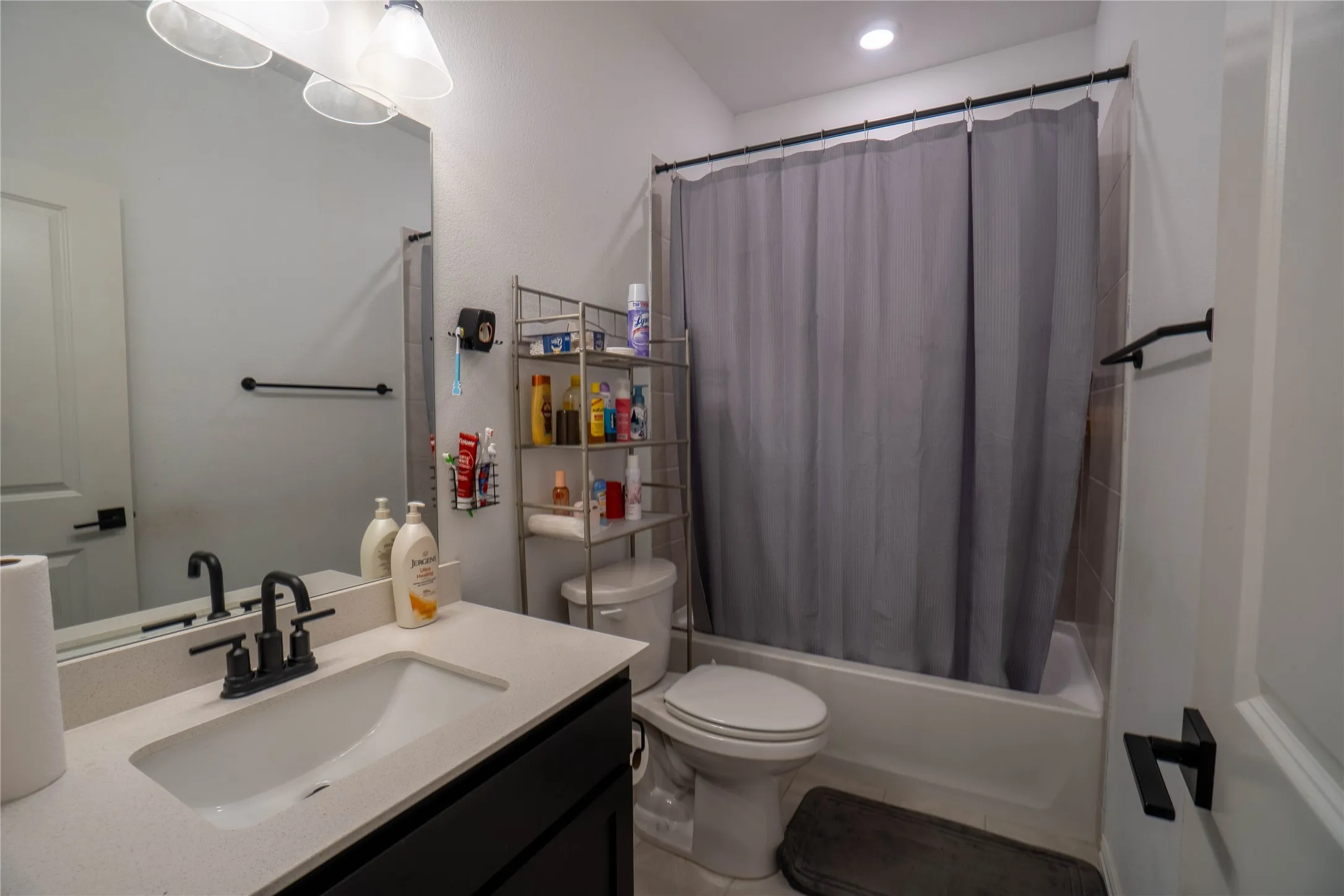 Bathroom featuring a single vanity with stone-finish countertop, undermount sink, and matte black faucet